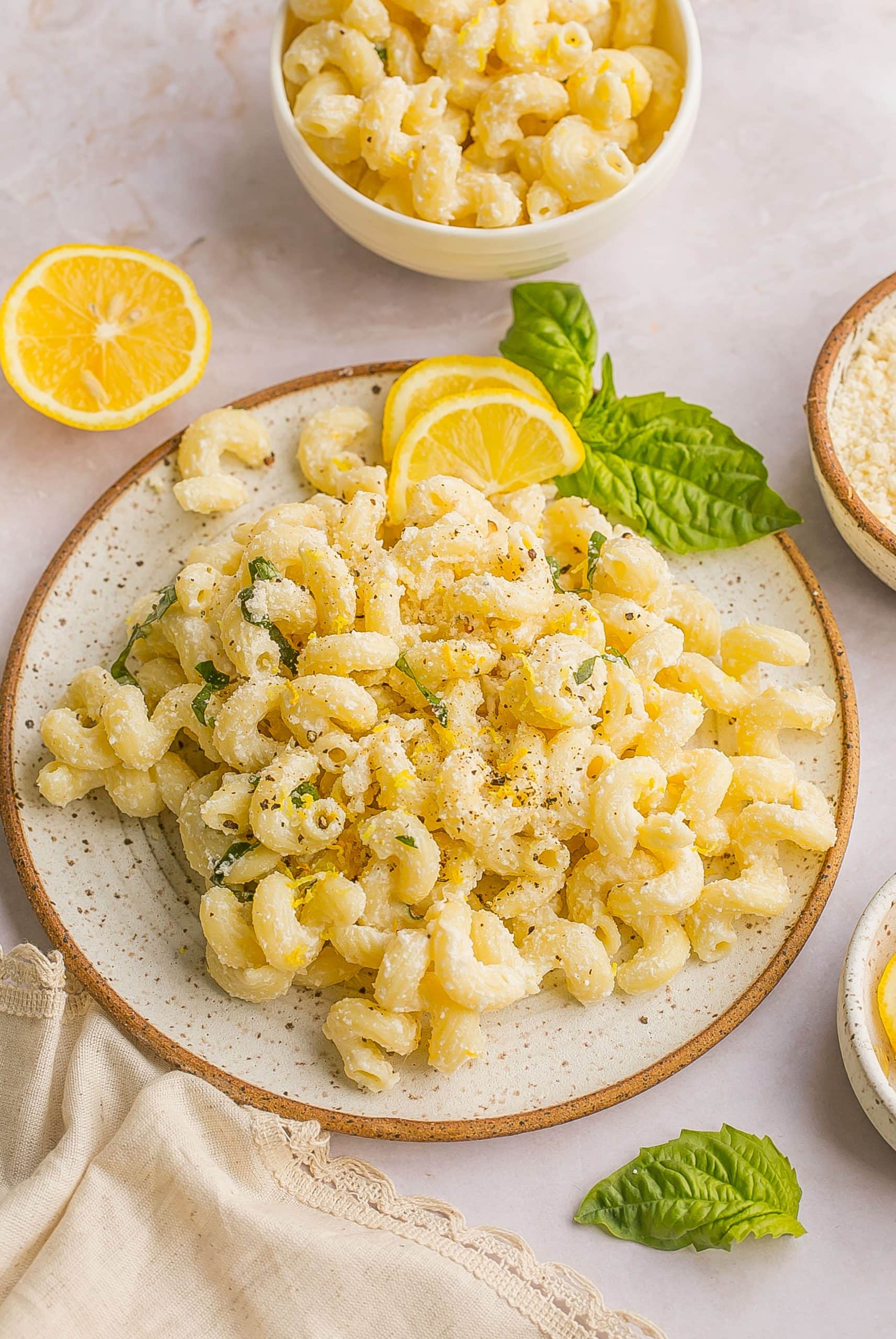 One Pot Pasta with Ricotta and Lemon on a plate garnished with fresh lemons and basil.
