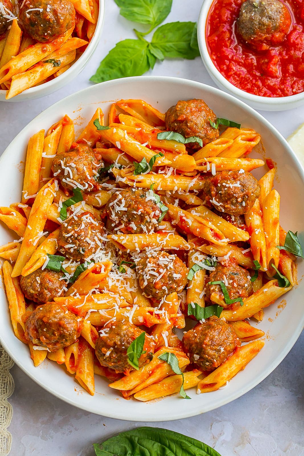 Meatball and pasta in a white bowl.