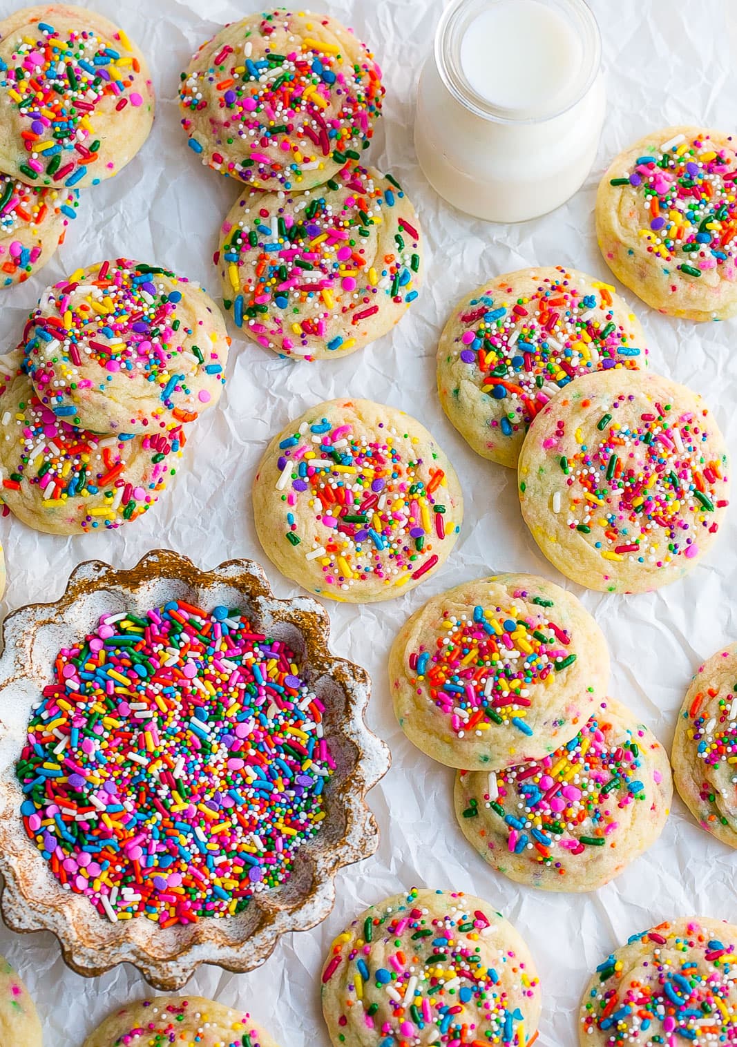Baked sugar cookies with rainbow sprinkles on parchment paper. 
