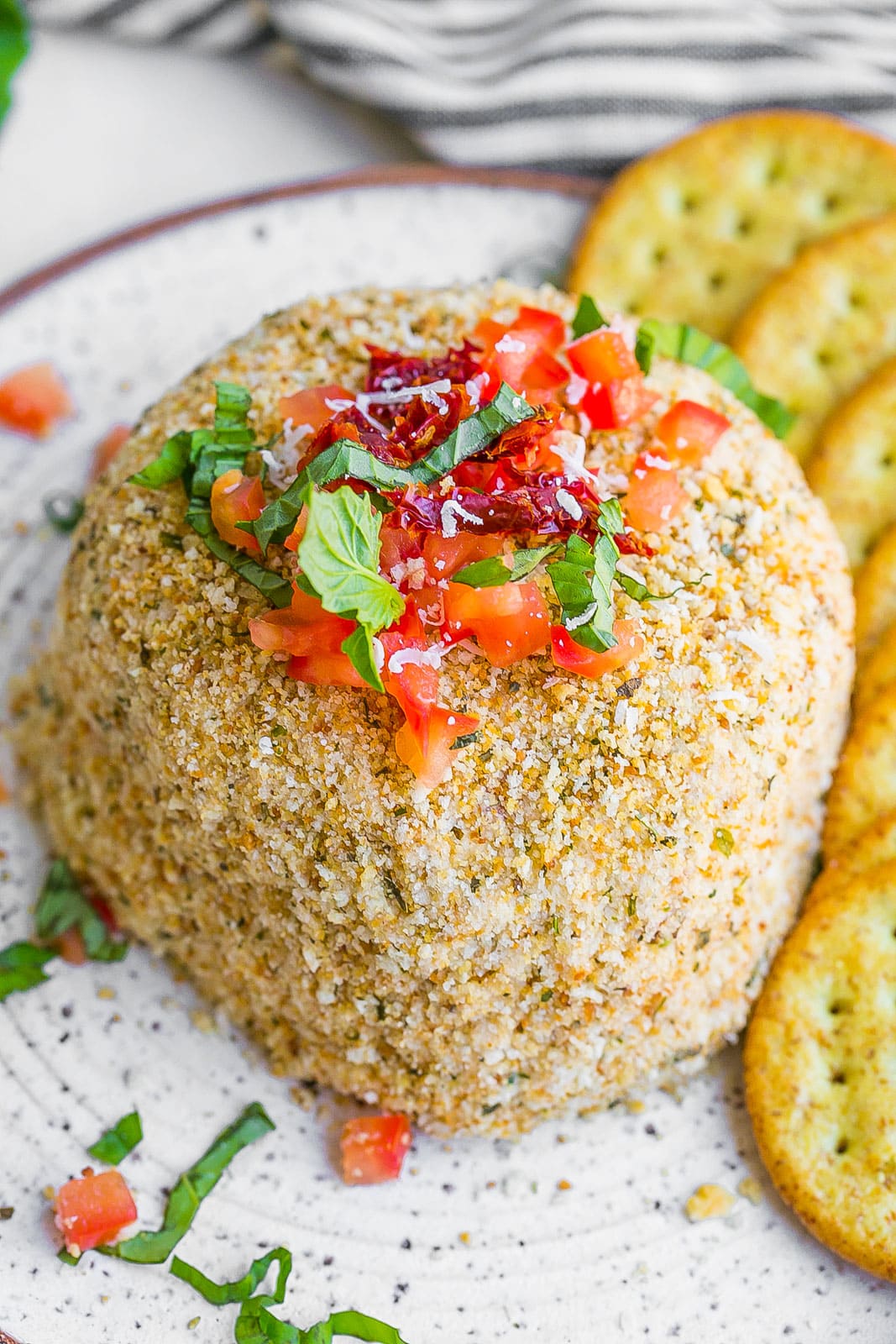 Bruschetta Cheese Ball on a plate with crackers.