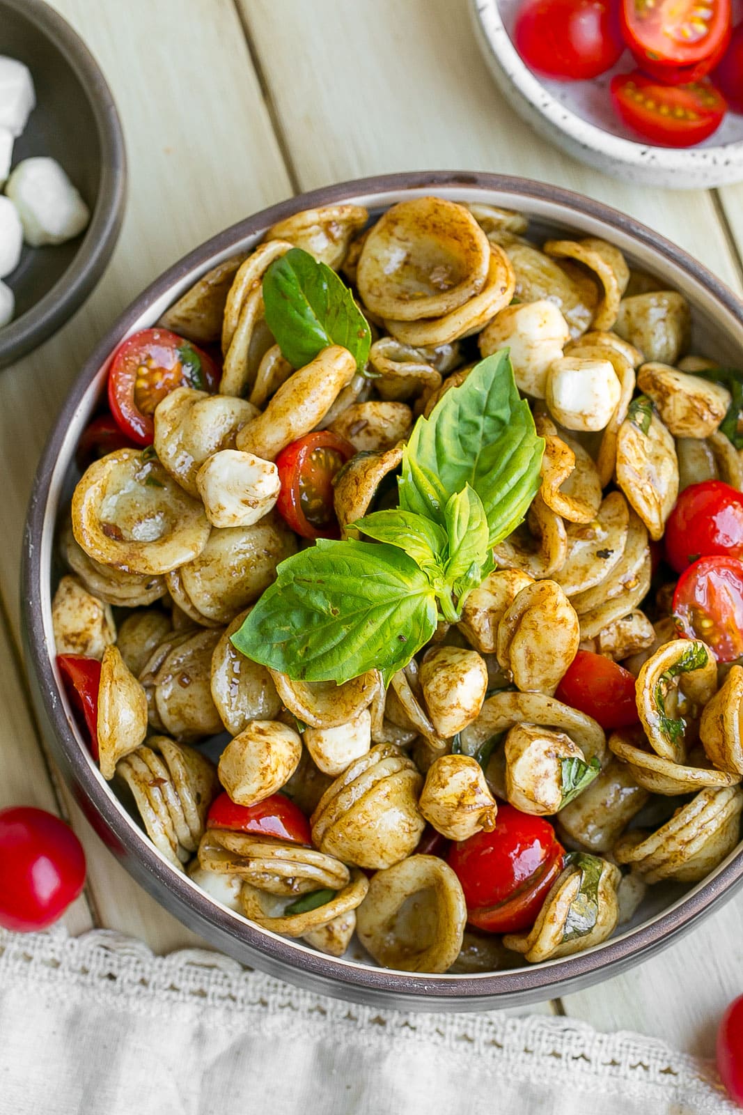 Pasta salad in a bowl with fresh basil on top.