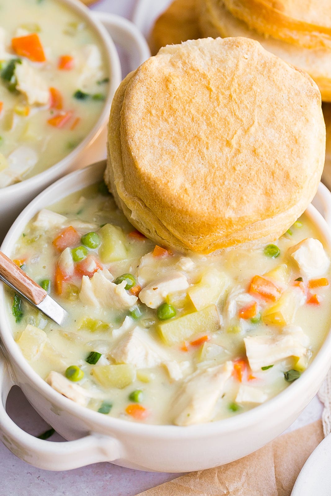 Healthy chicken pot pie soup in bowl with a spoon.