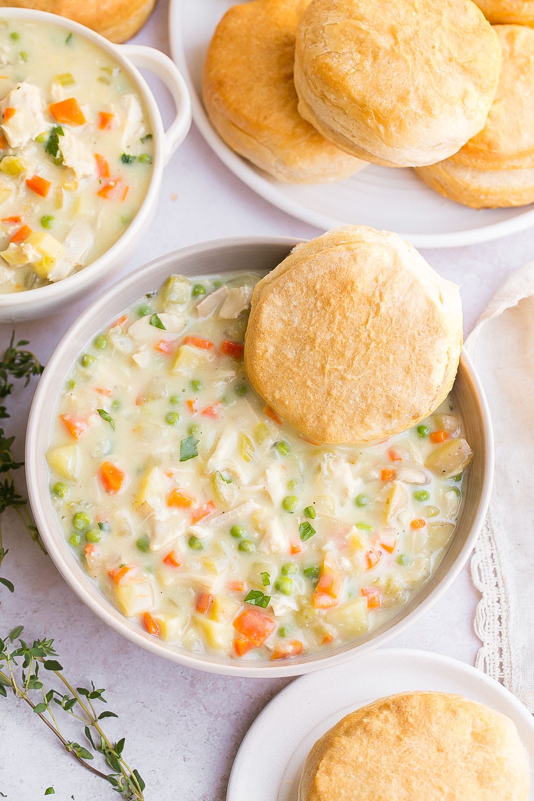 Large bowl with pot pie soup and a biscuit on the side.