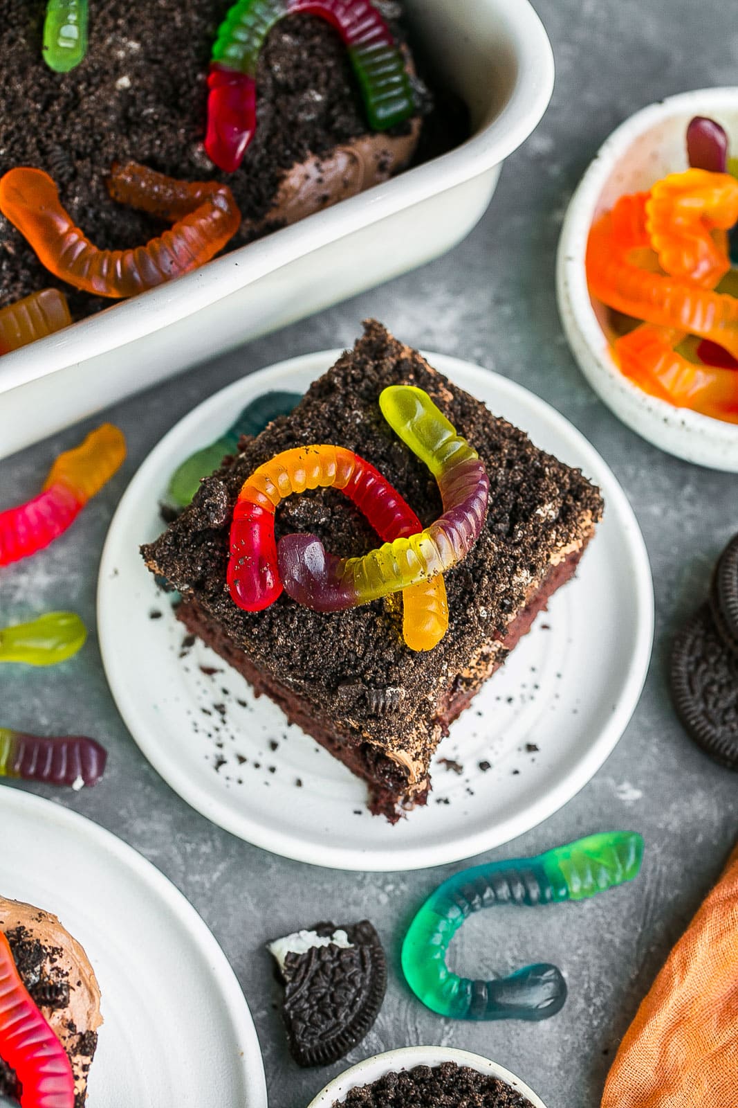 Chocolate cake with Oreos and gummy worms on top;.