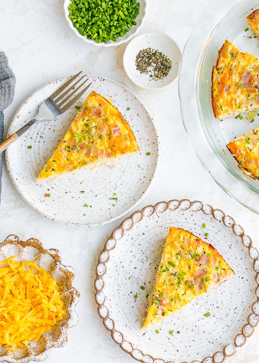 Frittata slices on plates with shredded cheese. 