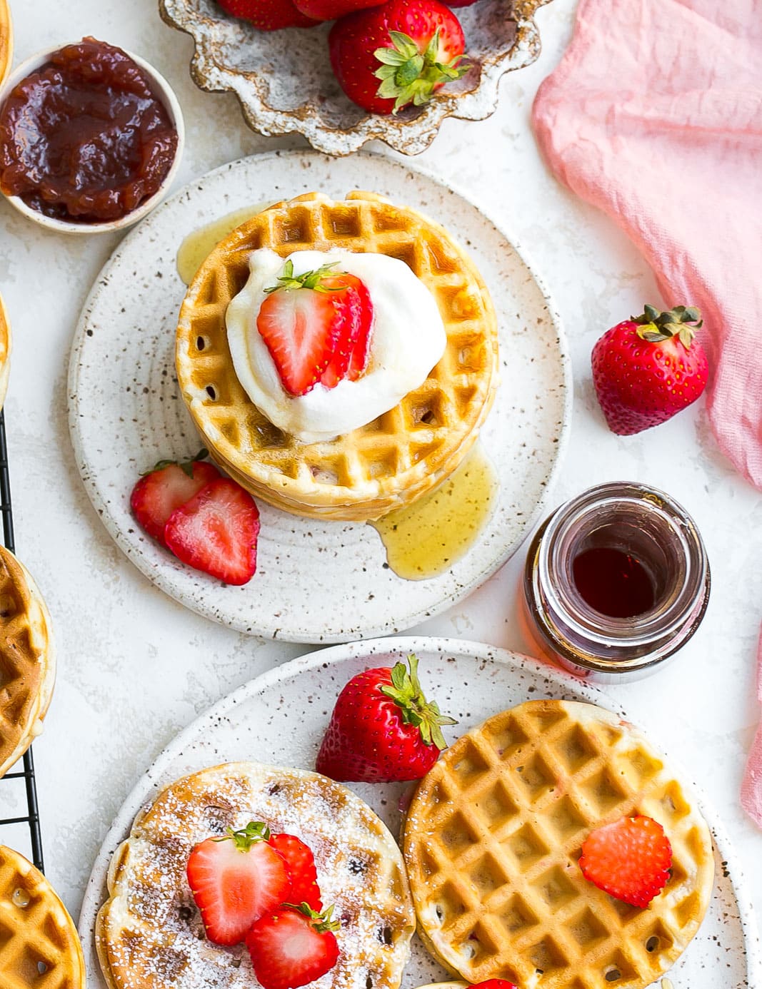 Waffles on a plate with strawberries on top.