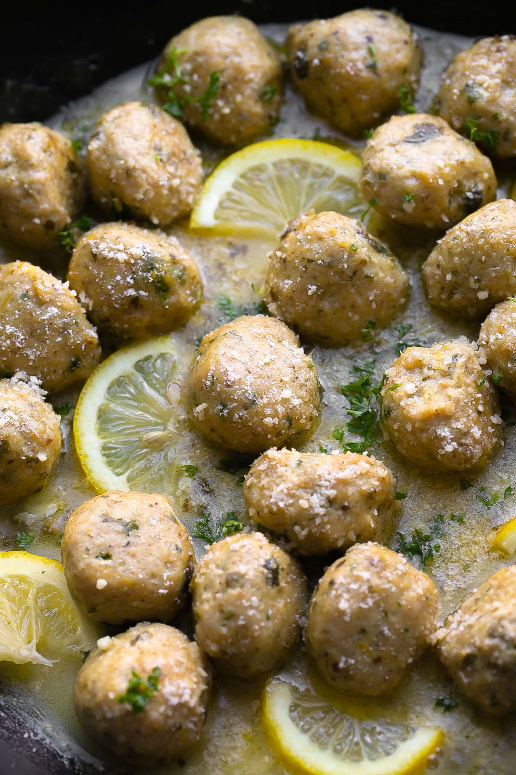 Meatballs in a pan with fresh lemons.