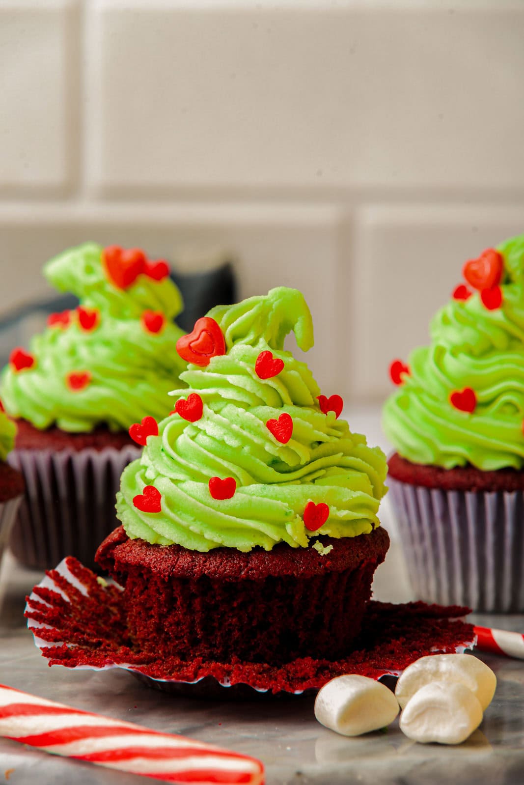 Red velvet grinch cupcakes with heart sprinkles.