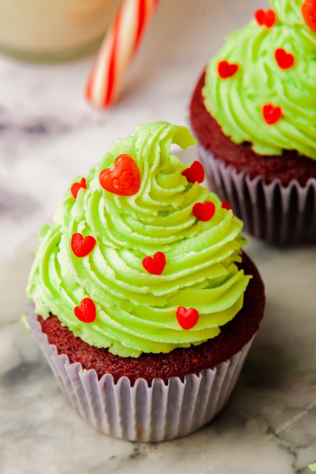 Red velvet cupcakes with green frosting and heart sprinkles.