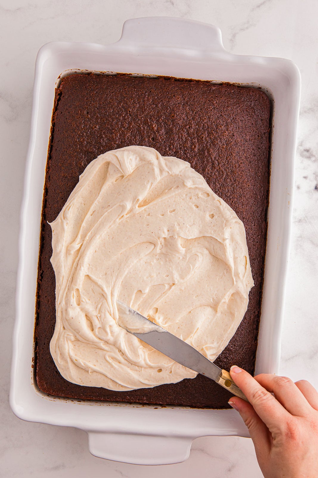 Frosting gingerbread cake with cream cheese frosting.