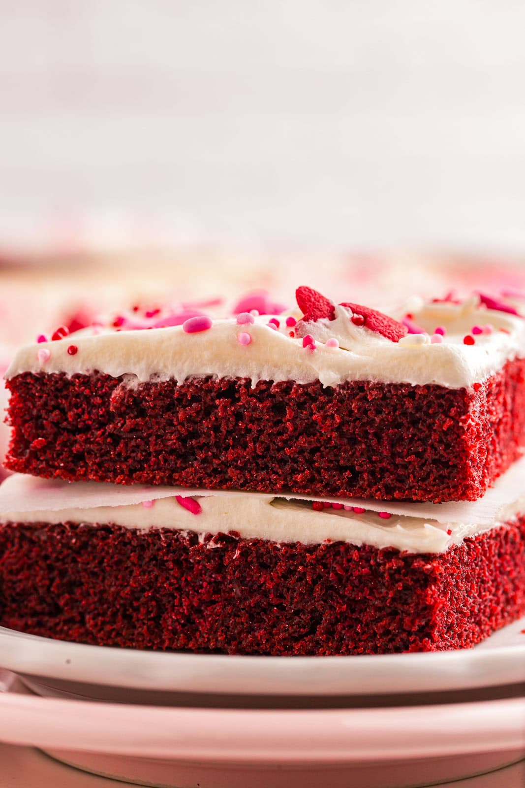 Stack of red velvet cake with cream cheese frosting and sprinkles.