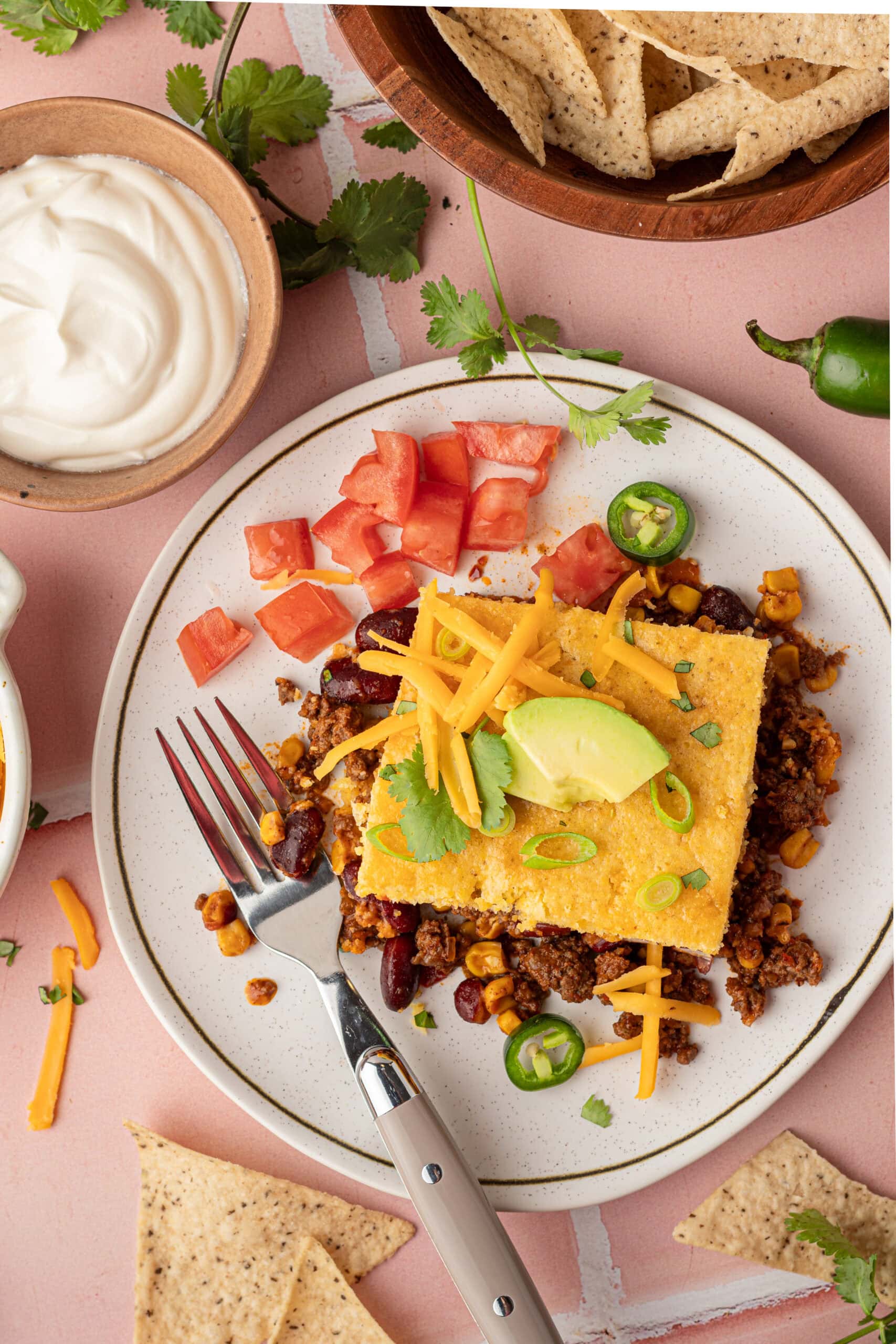 Taco Cornbread Casserole on a plate garnished with taco toppings. 