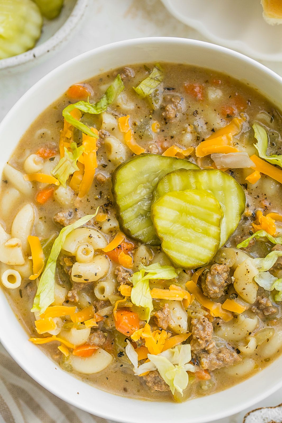 Close up of cheeseburger soup with fixings on top.