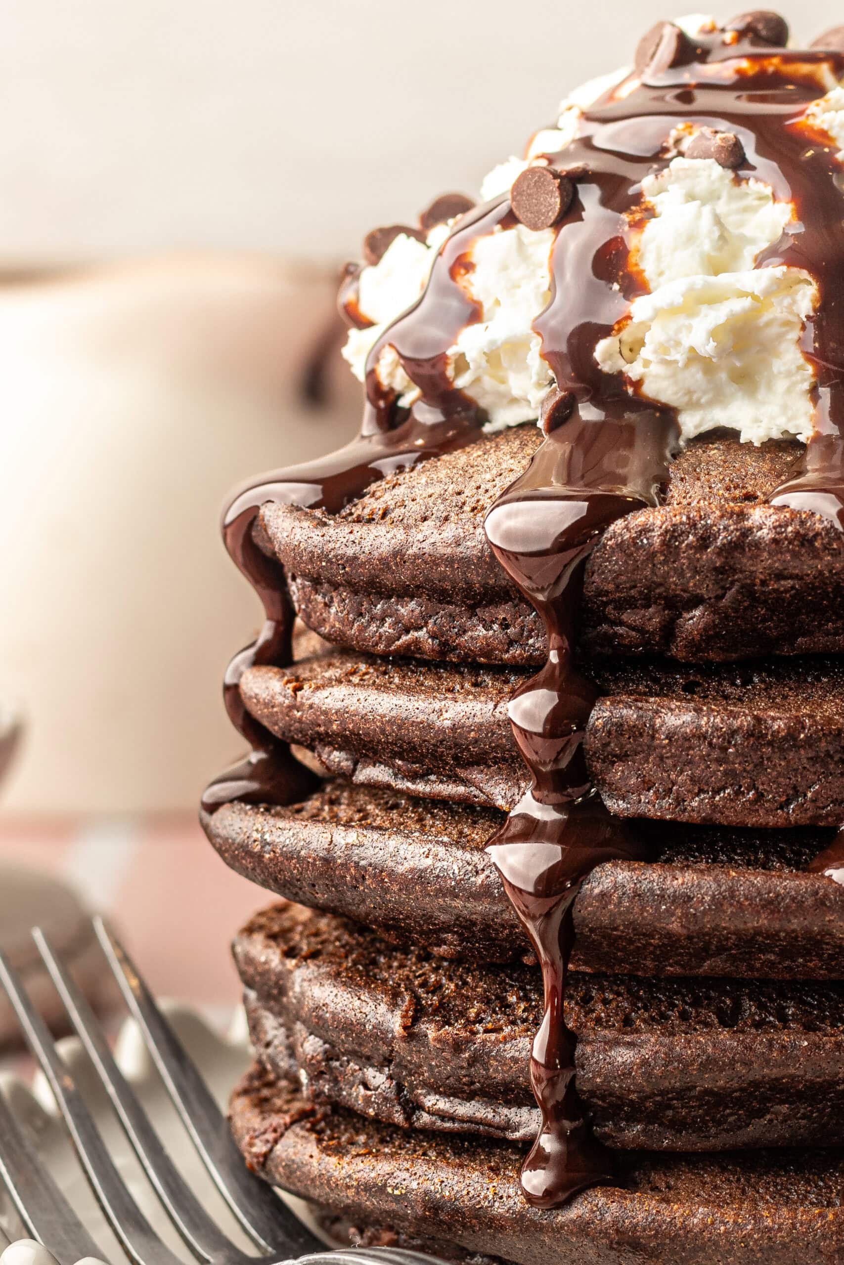 Stack of Chocolate Pancakes with chocolate sauce dripping on the sides.