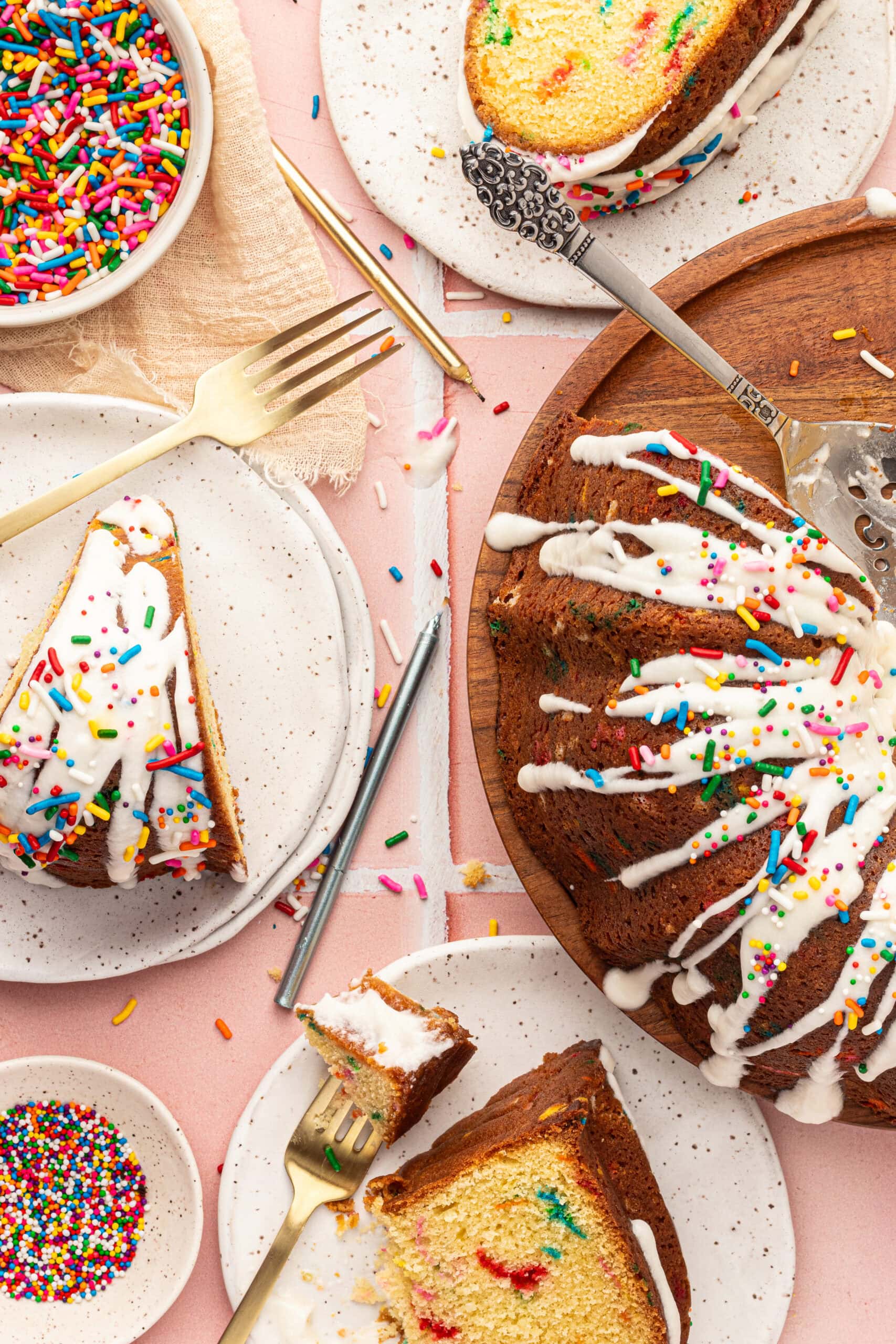 Birdseye view of a few slices of funfetti cake on plates with candles.