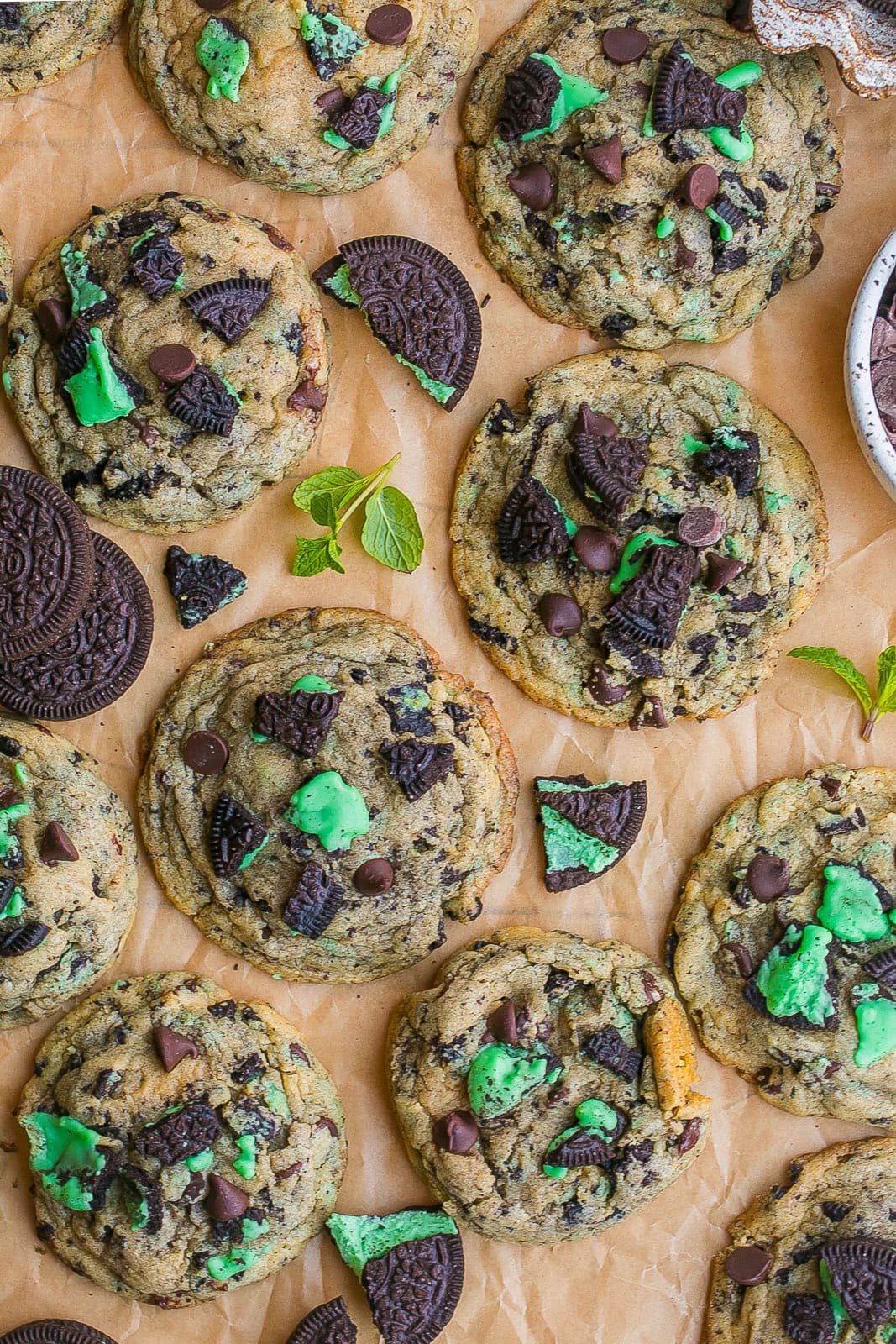 Mint Oreo Cookies on parchment paper with whole Oreo cookies and fresh mint.