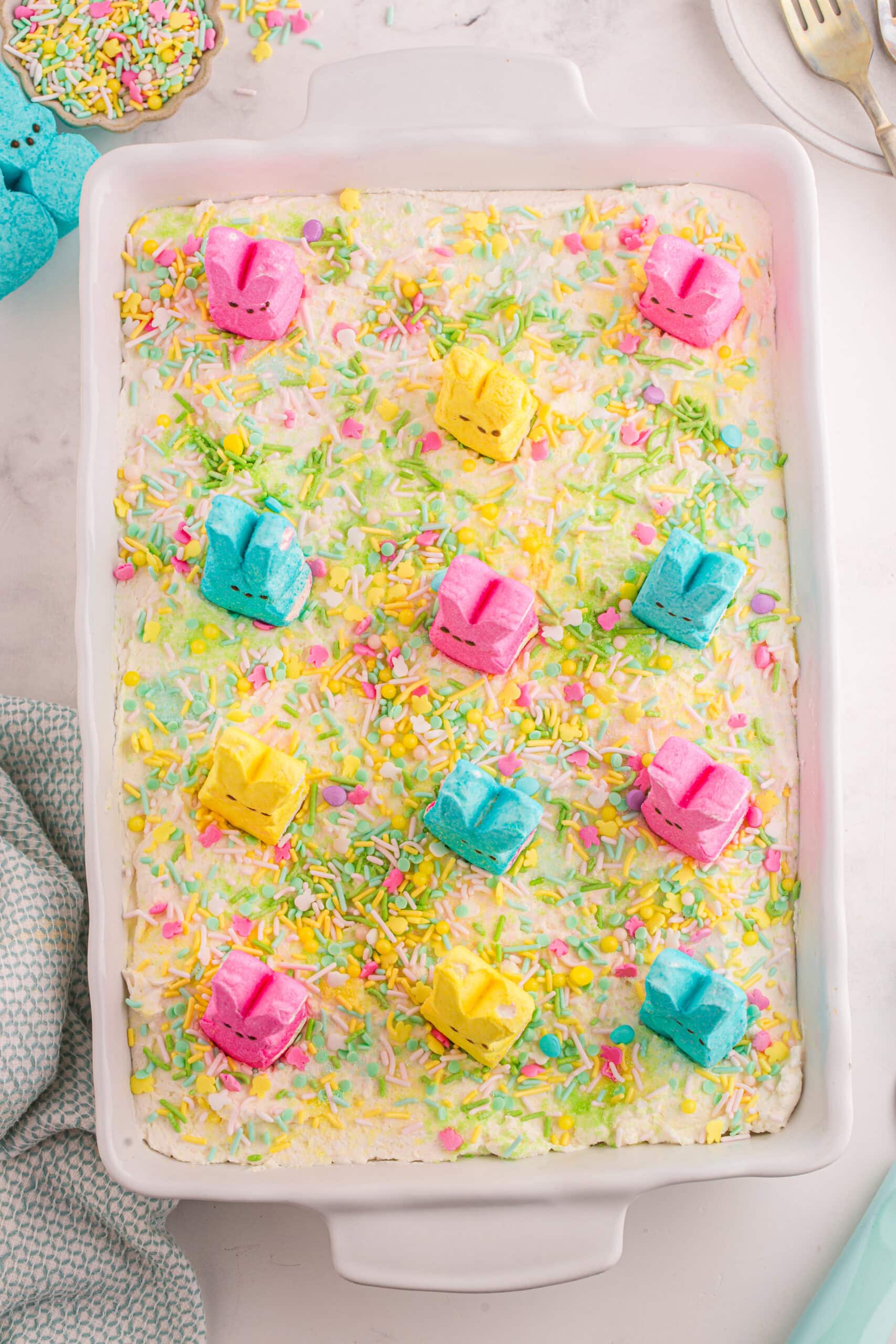 Birds eye view of Easter Poke Cake with marshmallow bunnies and festive sprinkles.