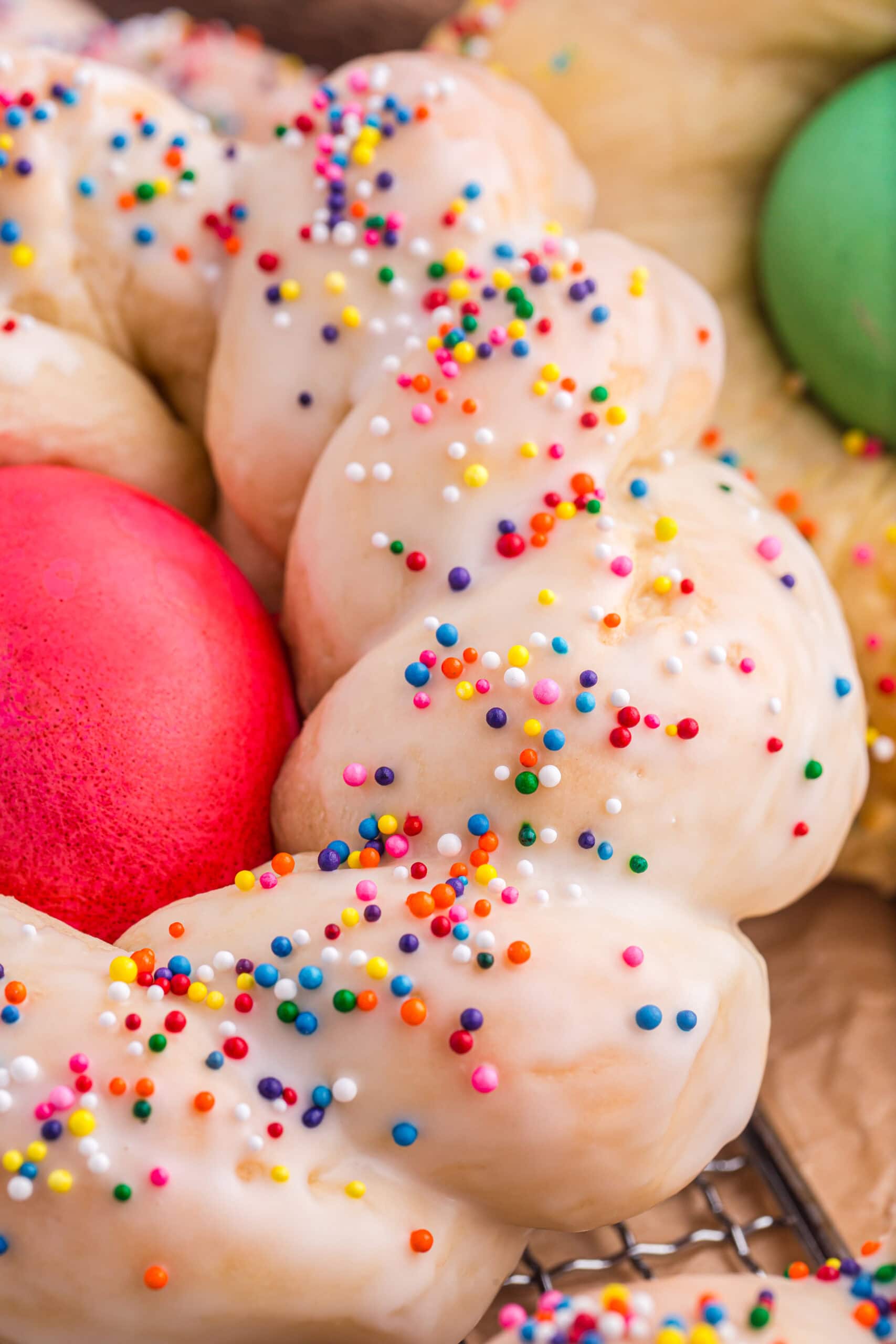 Close up of braid on bread with frosting and sprinkles.