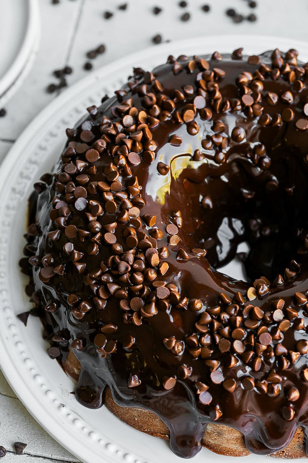 Ganache on top of cake with chocolate on white plate.