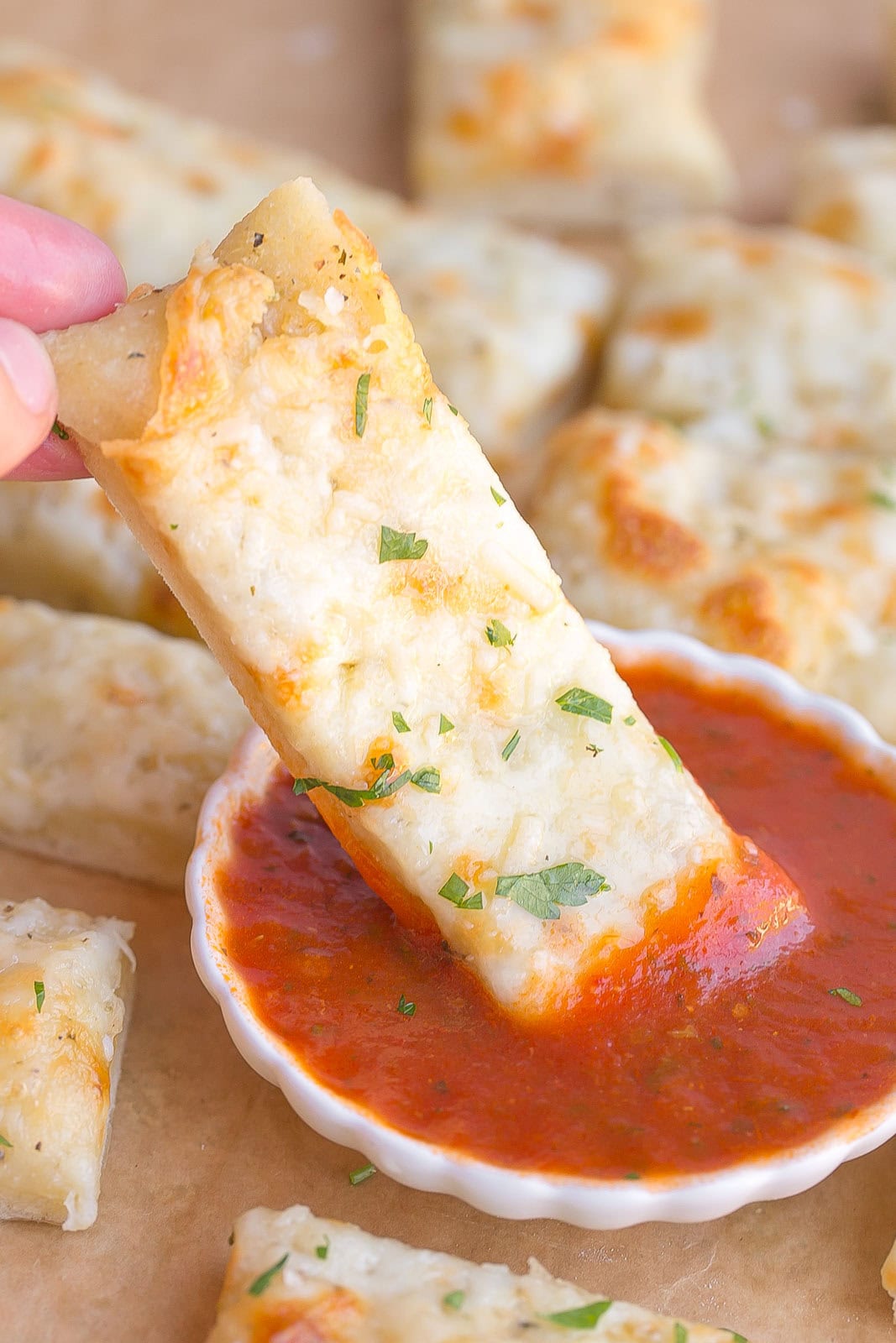 Bread stick getting dunked in red sauce.