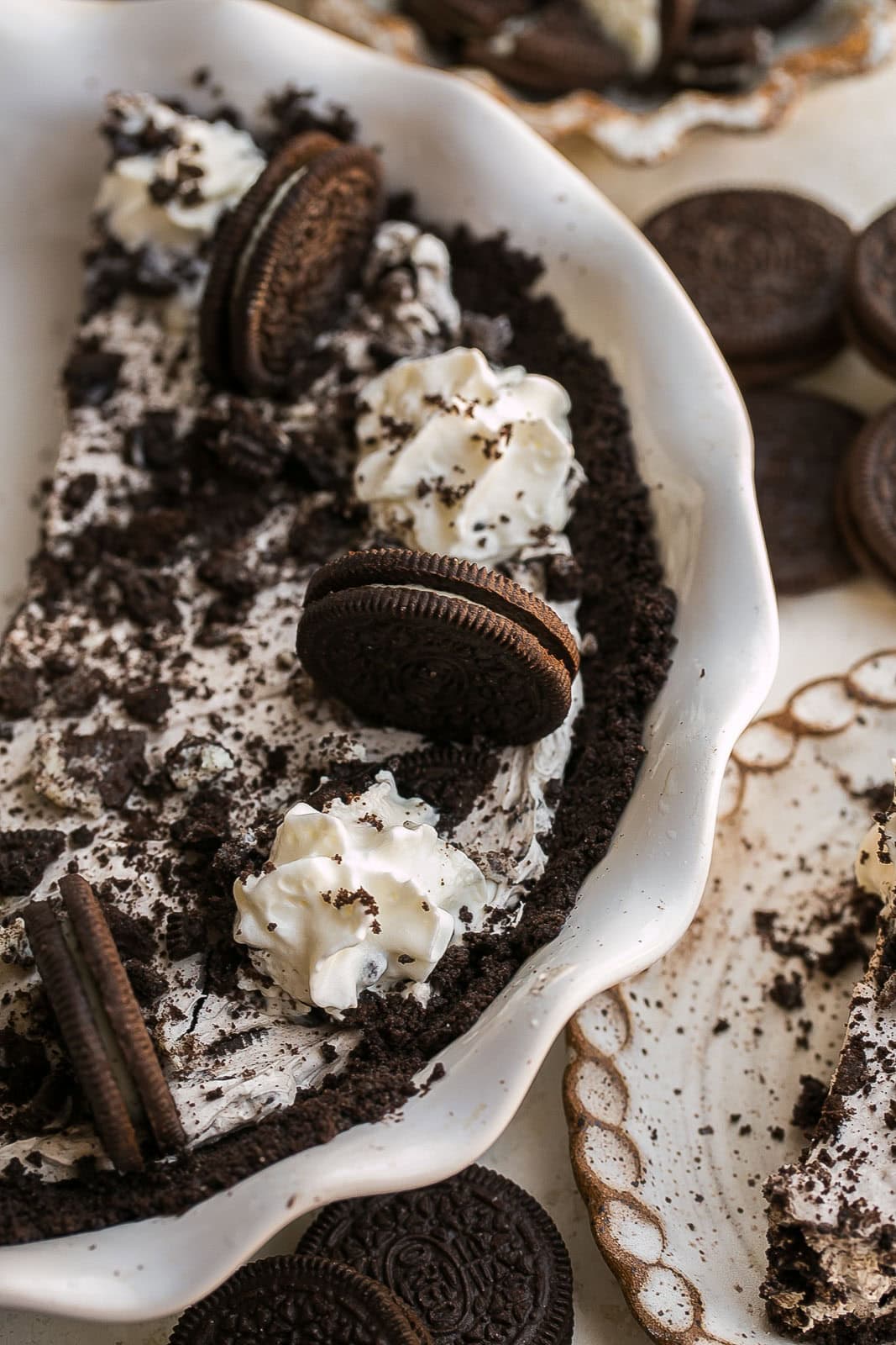 A side view of No Bake Oreo Pie with whipped cream and Oreeo on top.
