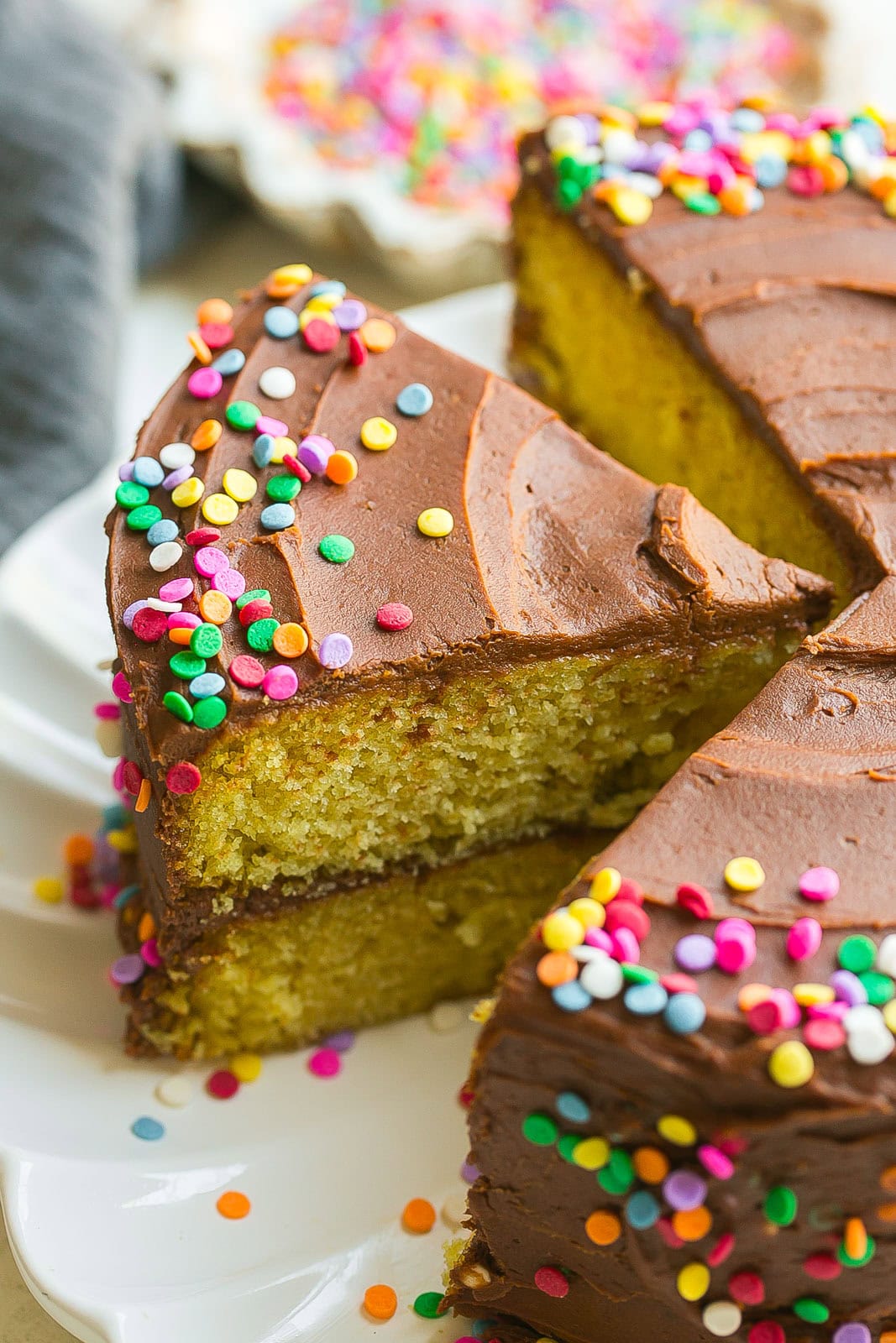 A beautiful slice of yellow birthday cake with chocolate frosting.