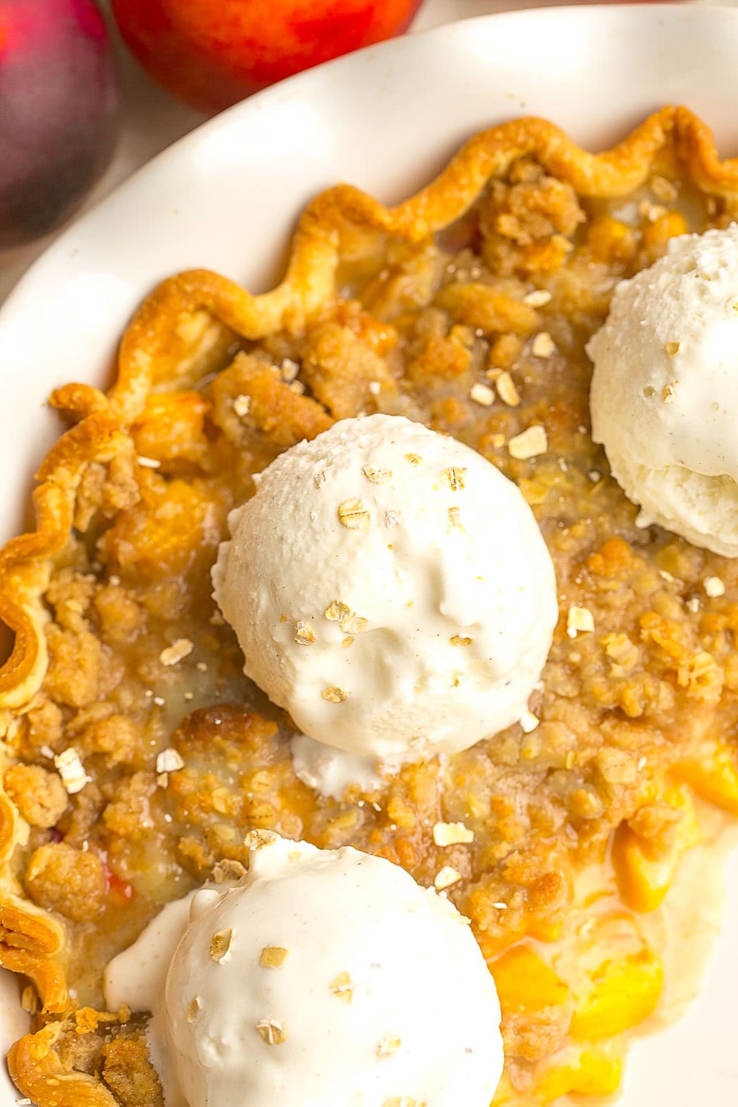 Scoop of vanilla ice cream on peach pie.