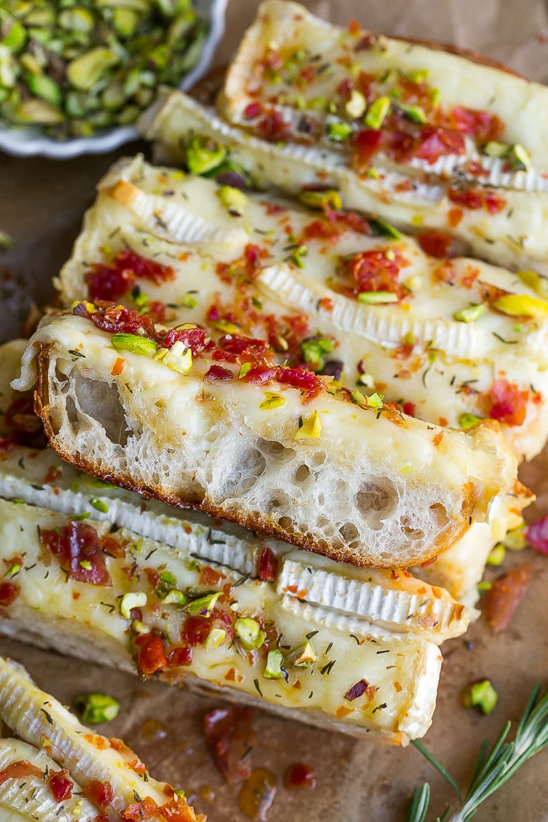 Side view of a piece of bread with baked brie cheese on top.