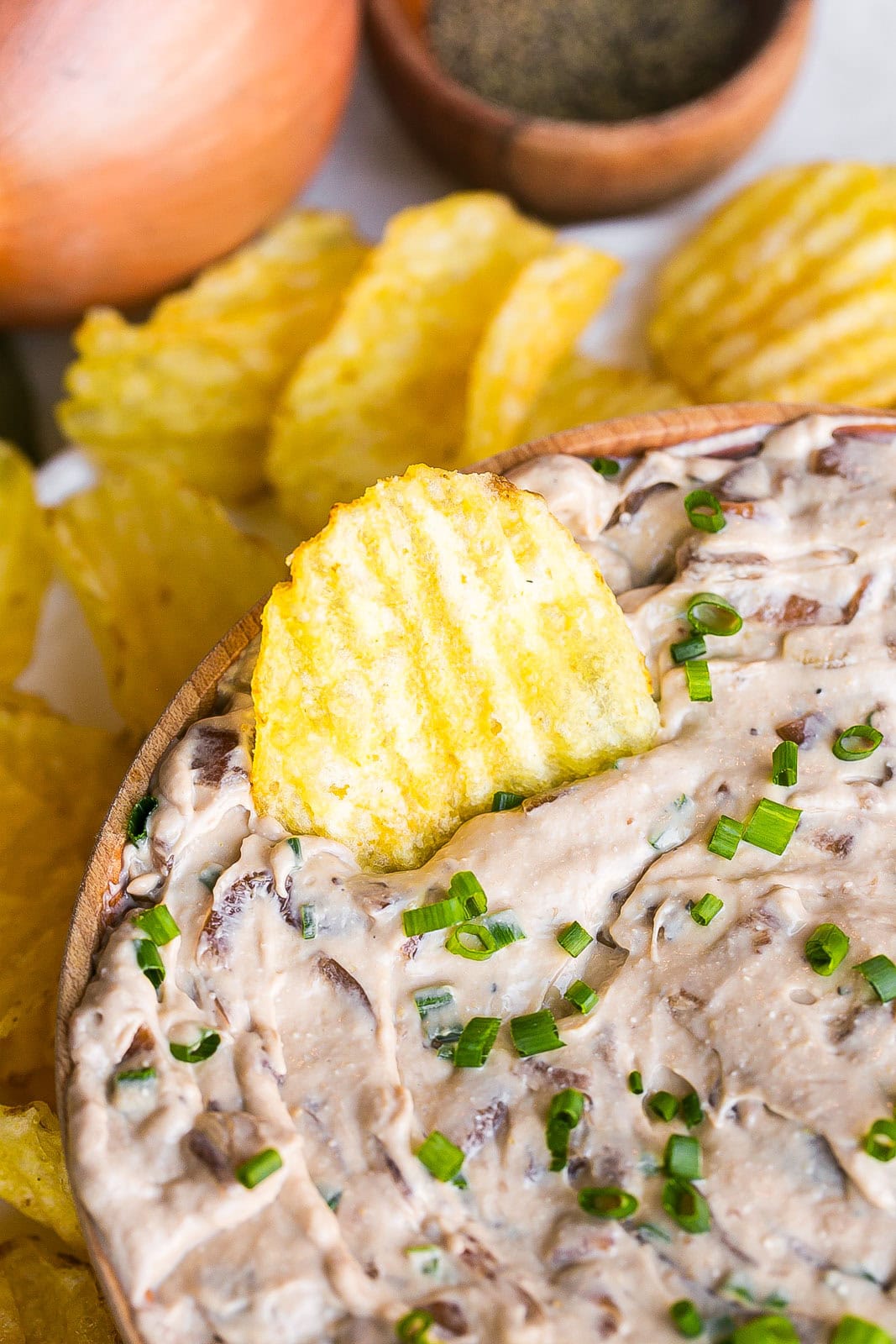Side view of a party dip with potato chip inside.