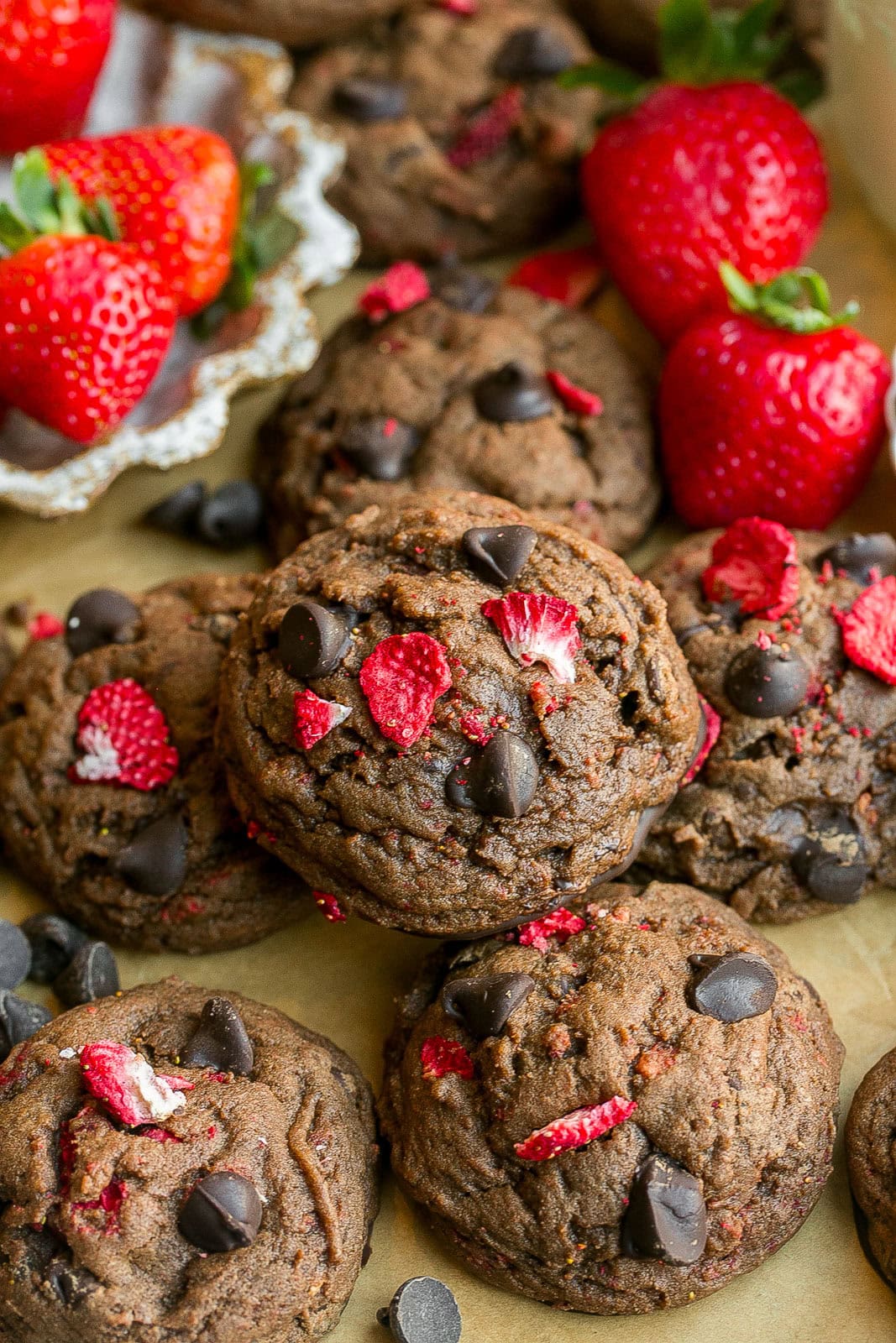 Chocolate cookies with freeze-dried strawberries on parchment paper.