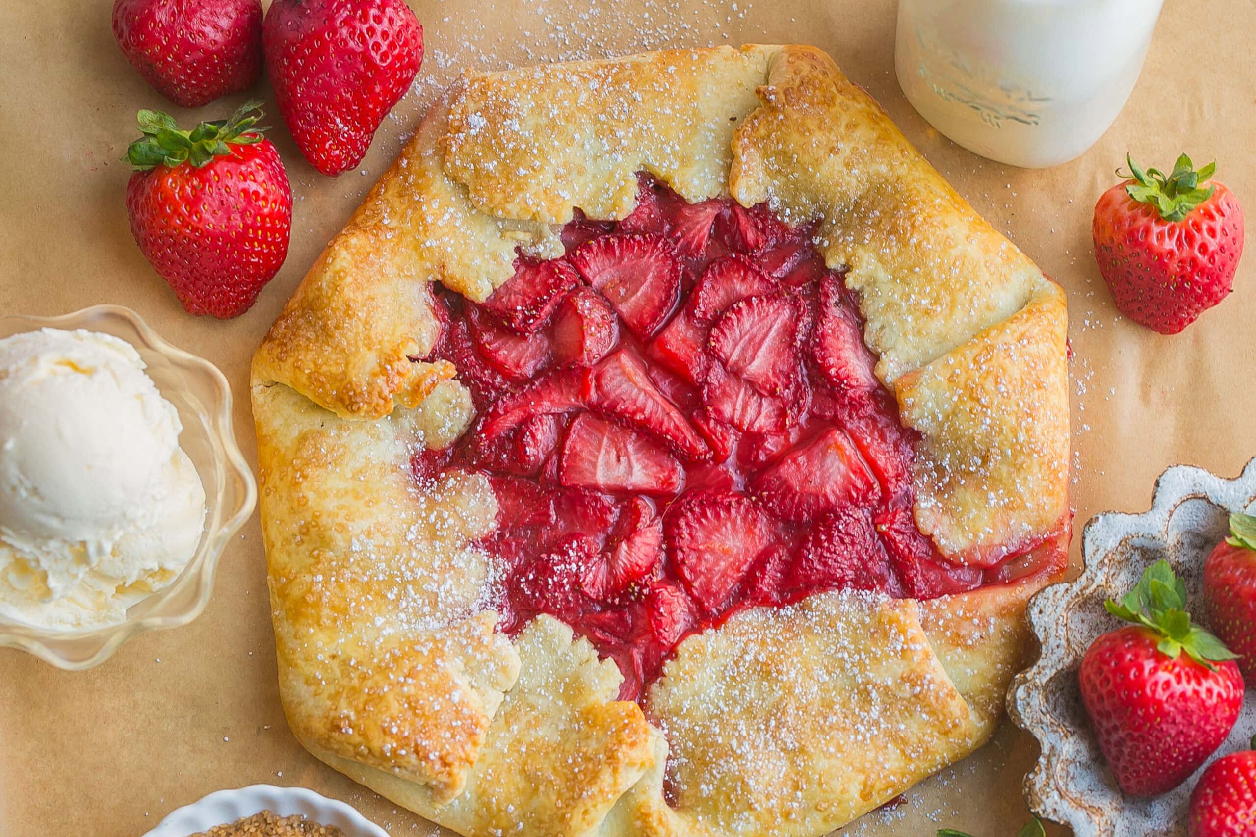 Rustic strawberry tart on parchment paper.