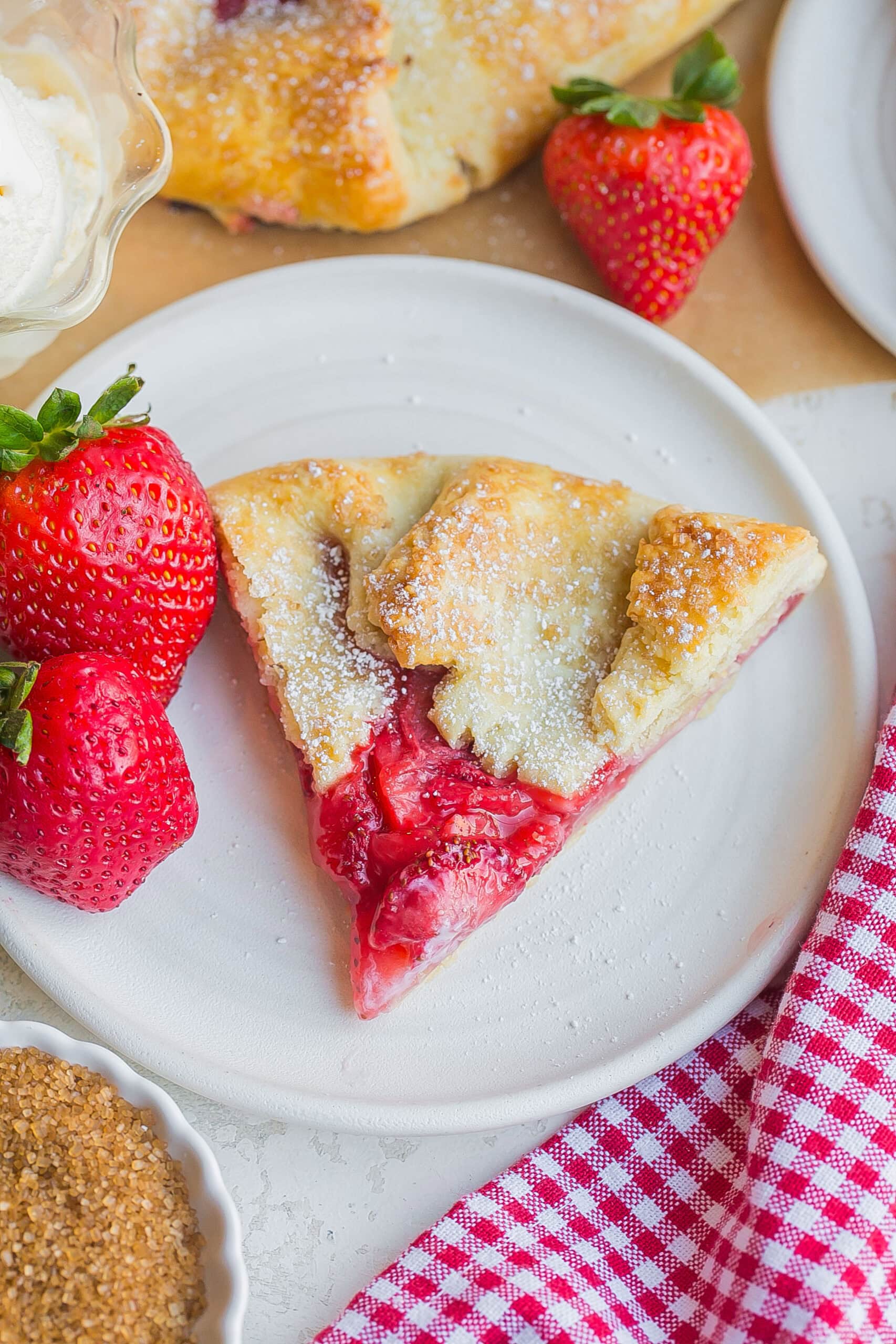 Slice of easy strawberry galette on white dish.