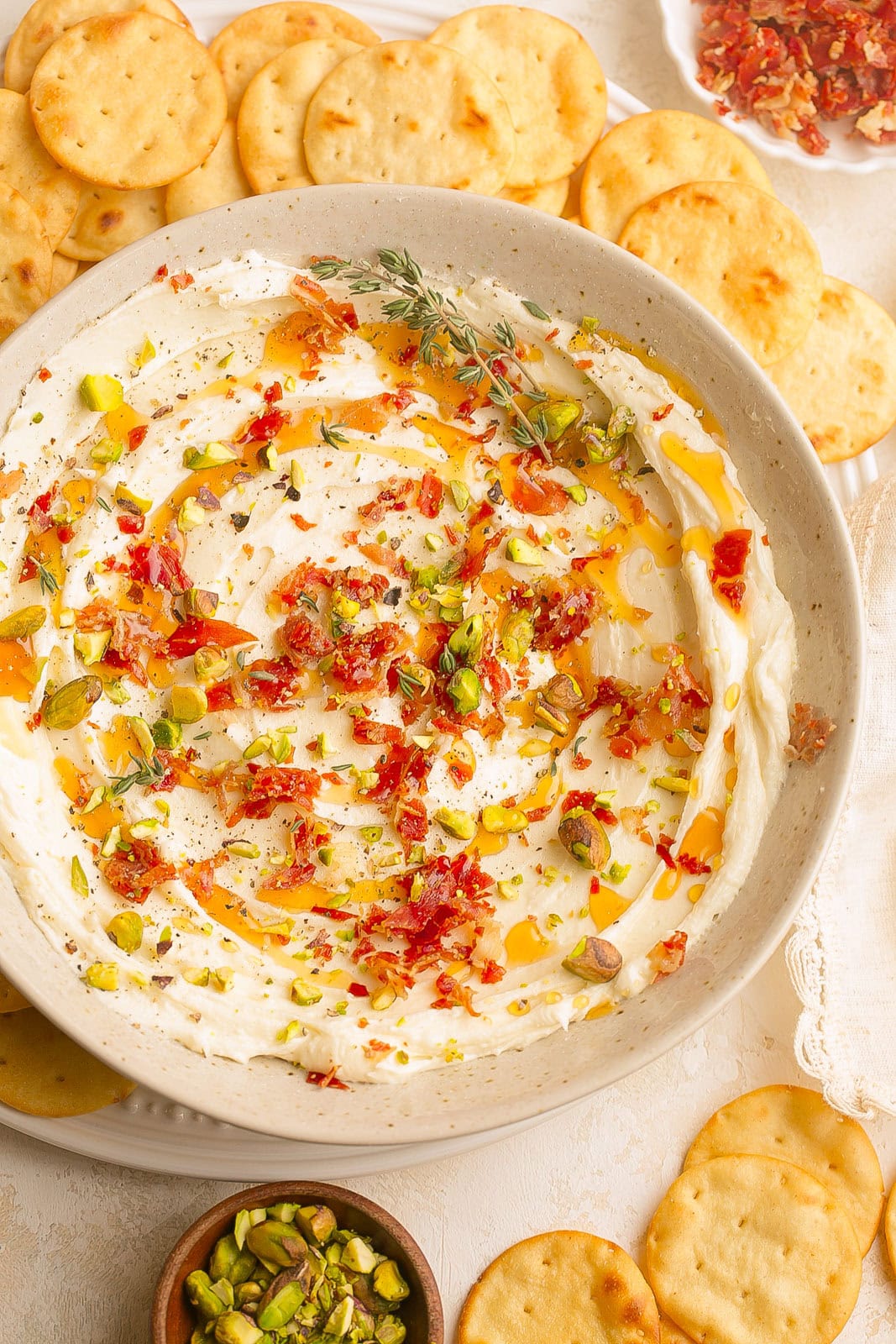 Whipped Brie Cheese Dip with hot honey, prosciutto pieces, pistachios and herbs.
