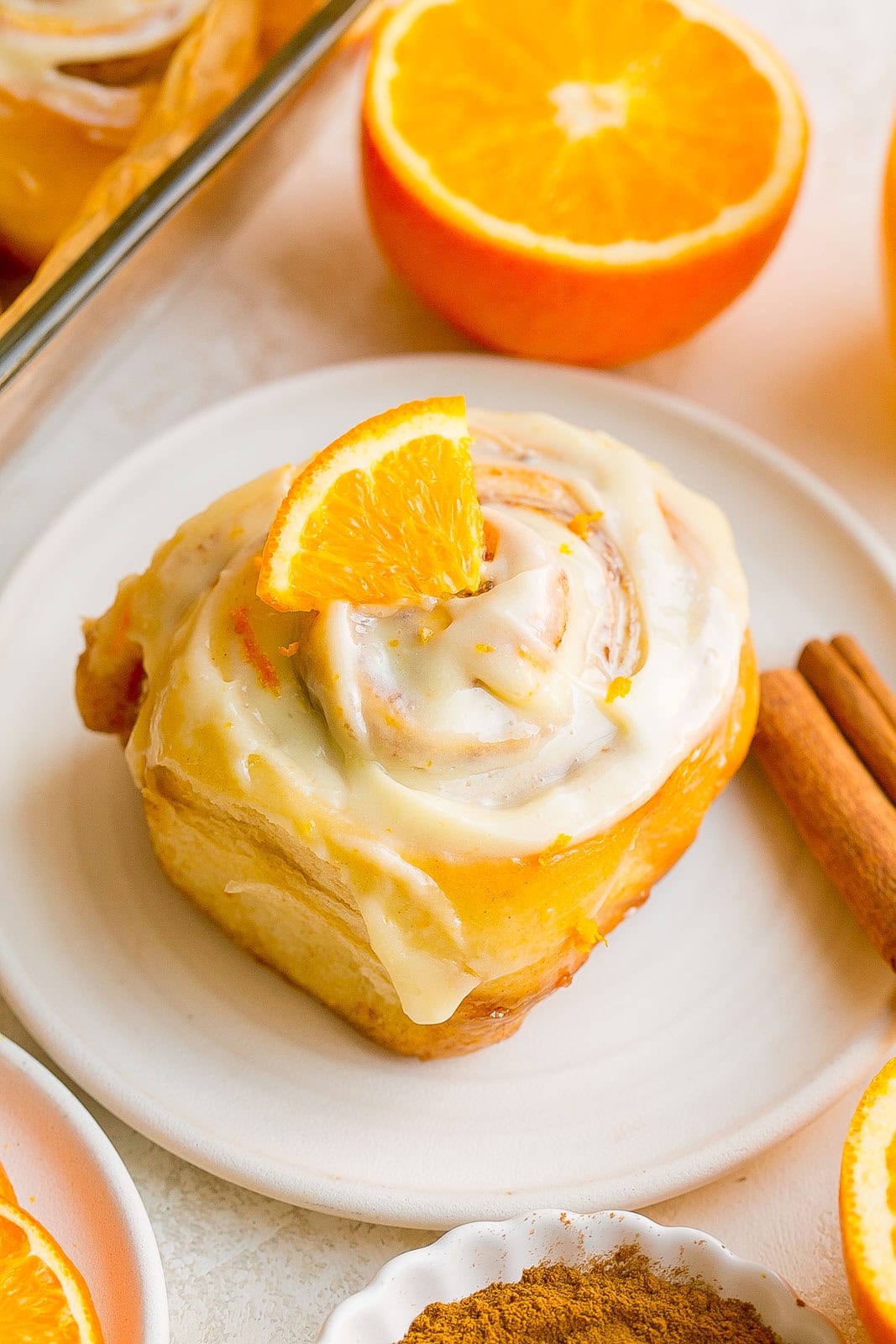 Fresh orange cinnamon rolls on a small white dish.