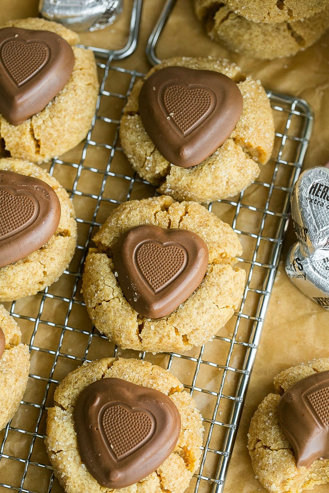 Chewy peanut butter cookies with chocolate heart on cooling rack.