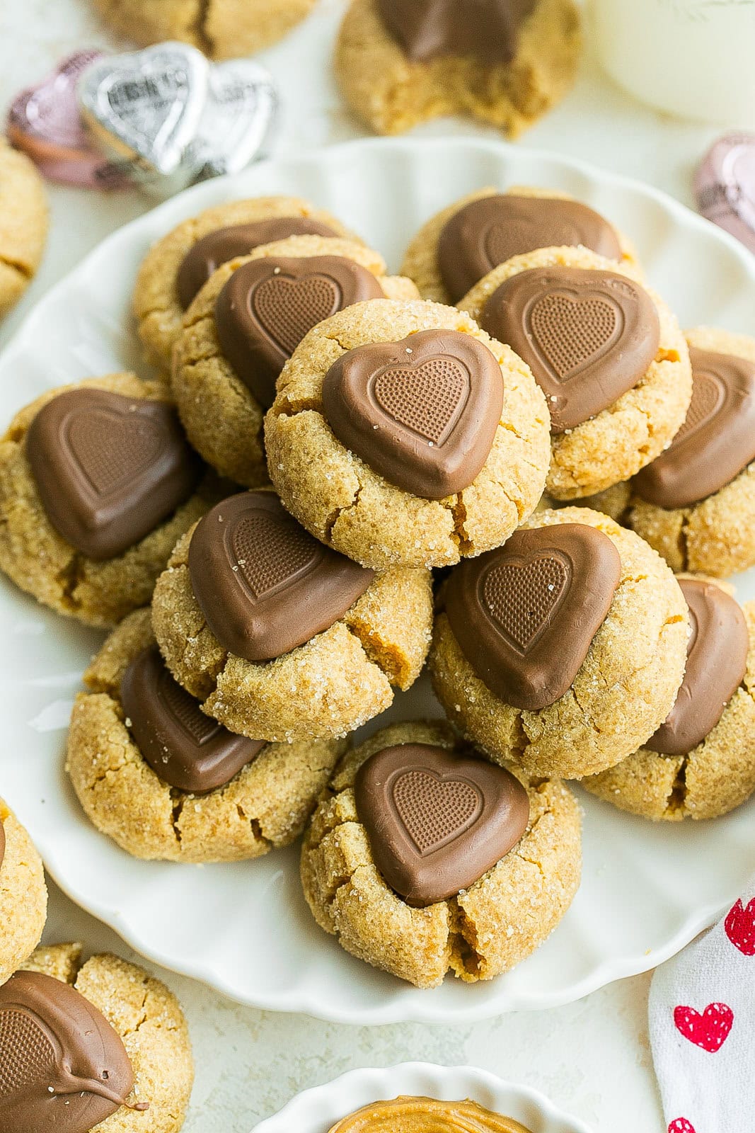 A white plate full of chewy peanut butter cookies with chocolate hearts.