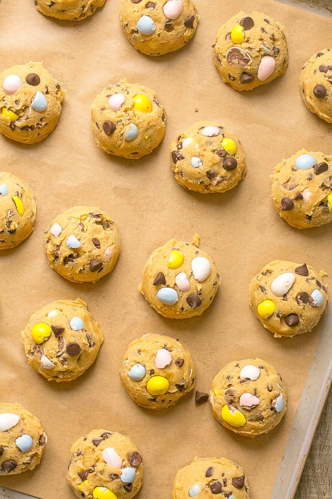 Dough balls on parchment paper of Mini egg cookie recipe.