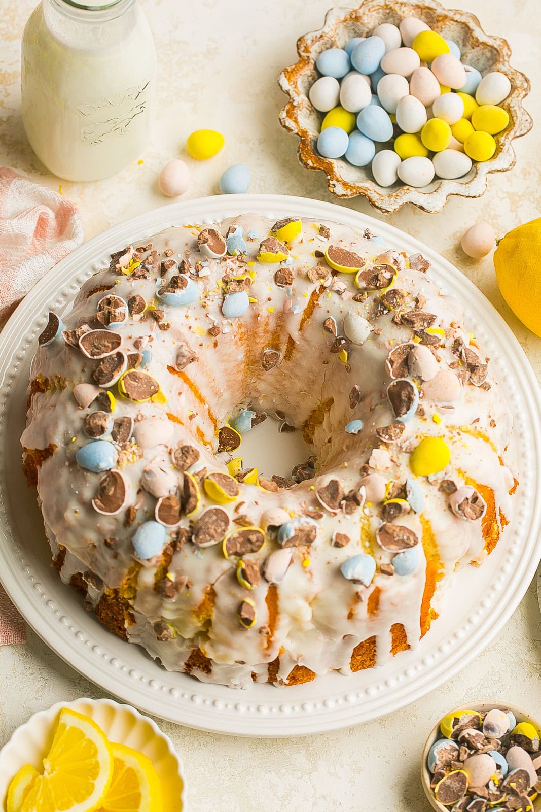 A whole Easter lemon cake, bundt cake with Cadbury mini eggs on a white plate.