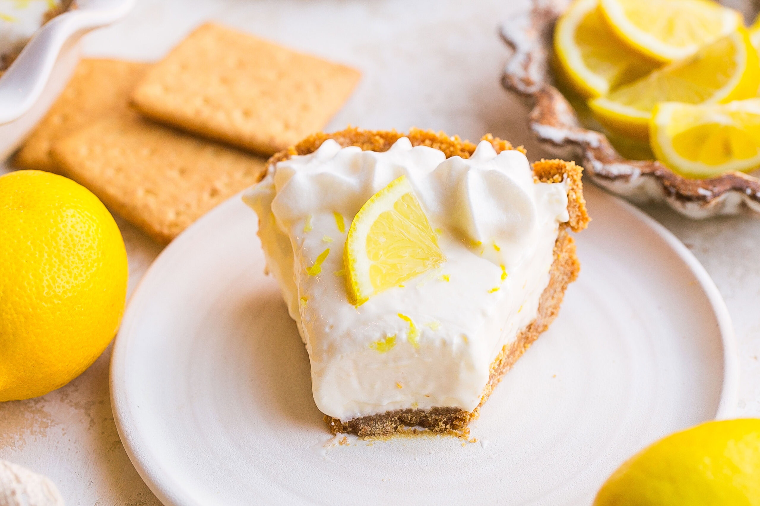 Creamy no bake Lemonade Pie with Cream Cheese in a graham cracker crust topped with fresh lemon slice.