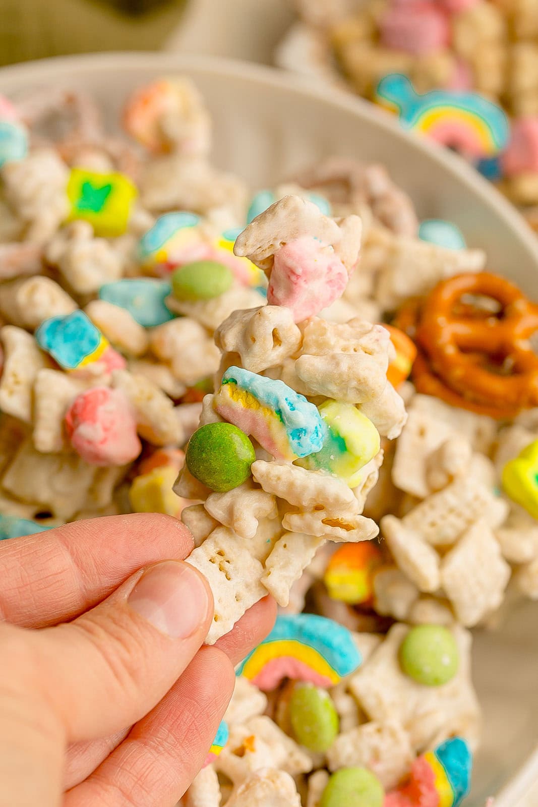 Hand holding Lucky Charms cereal snack mix.