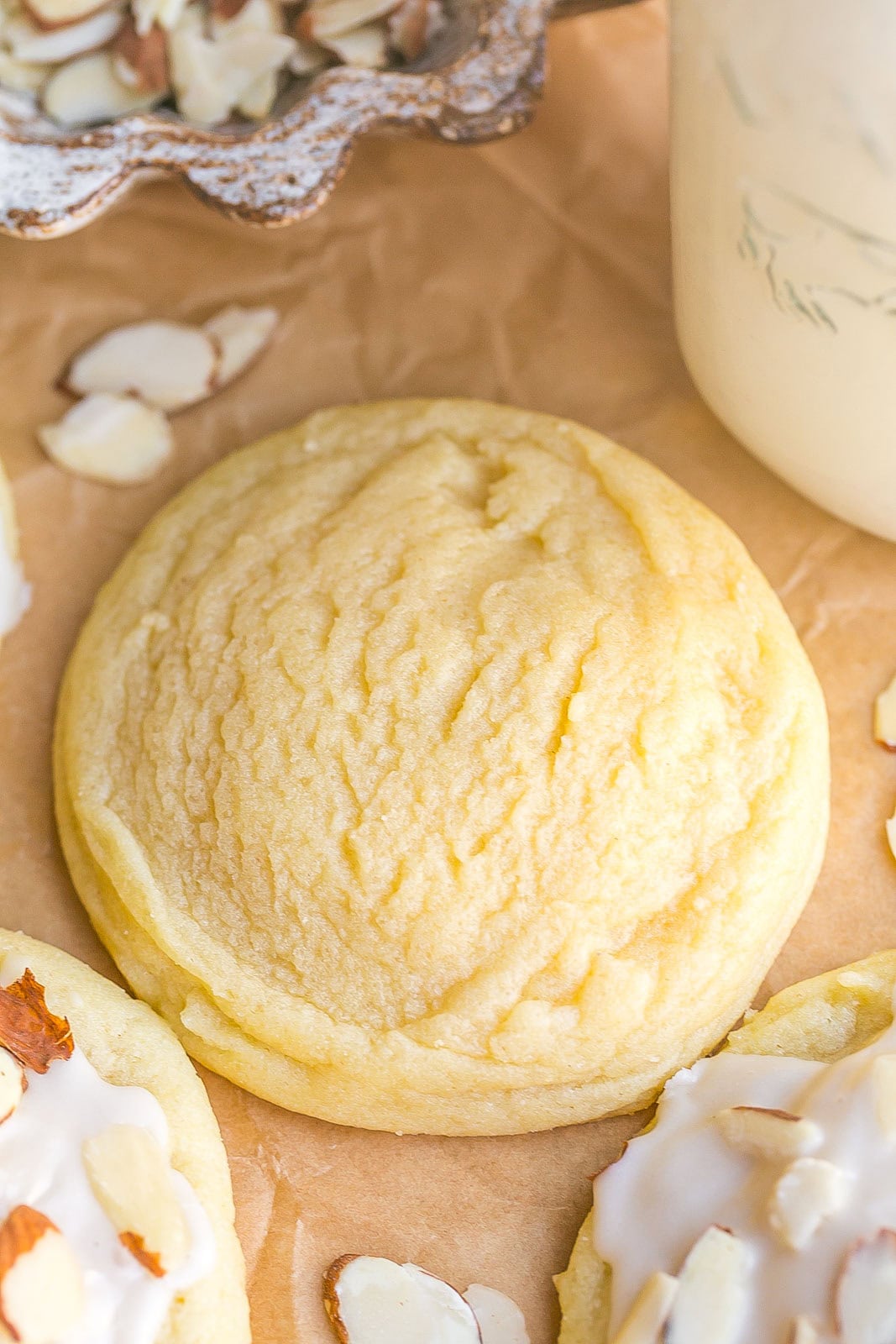 A plain sugar cookie with a glass of milk on the side.