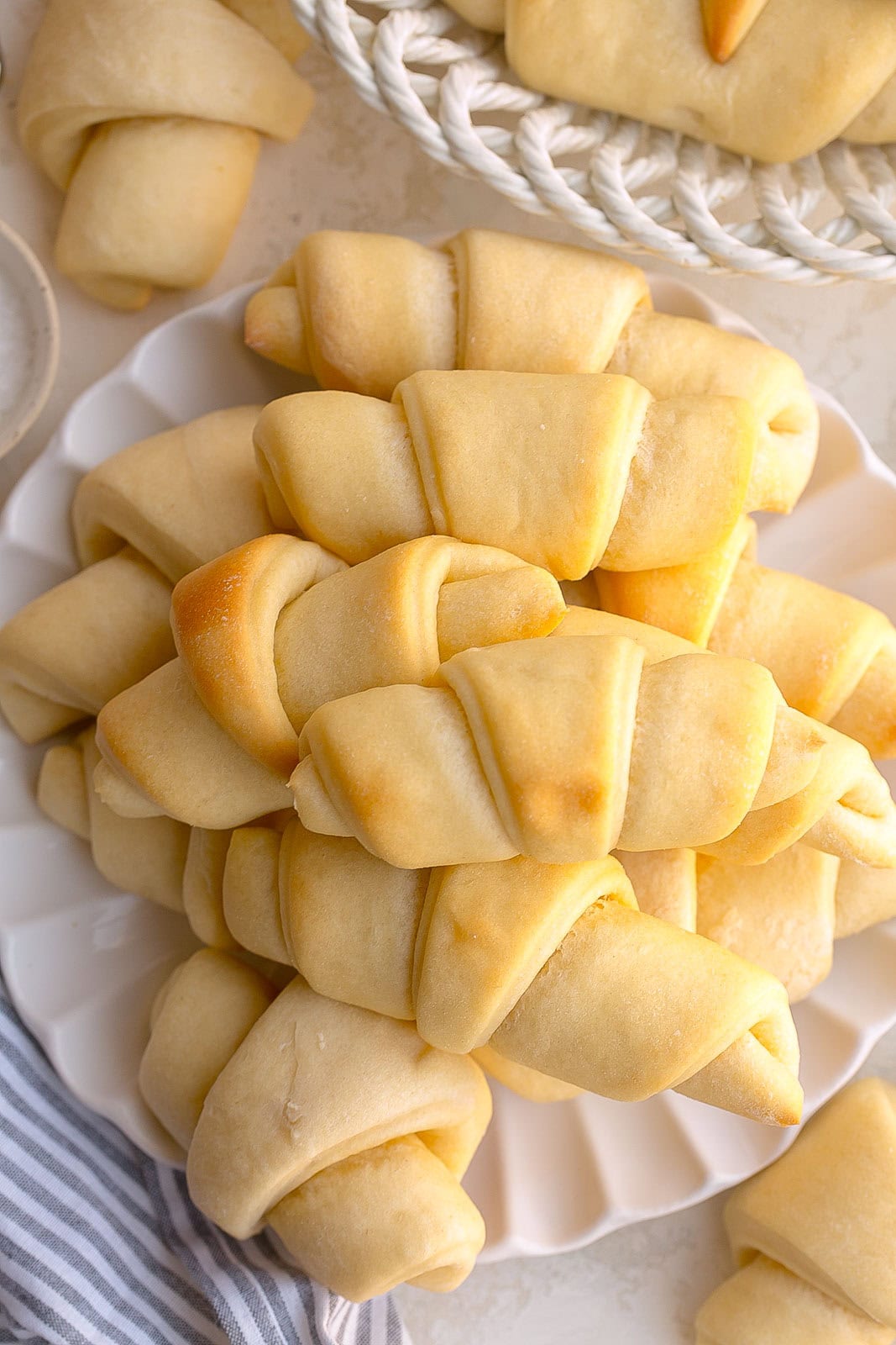 2 dozen buttery crescent rolls in a white dish.