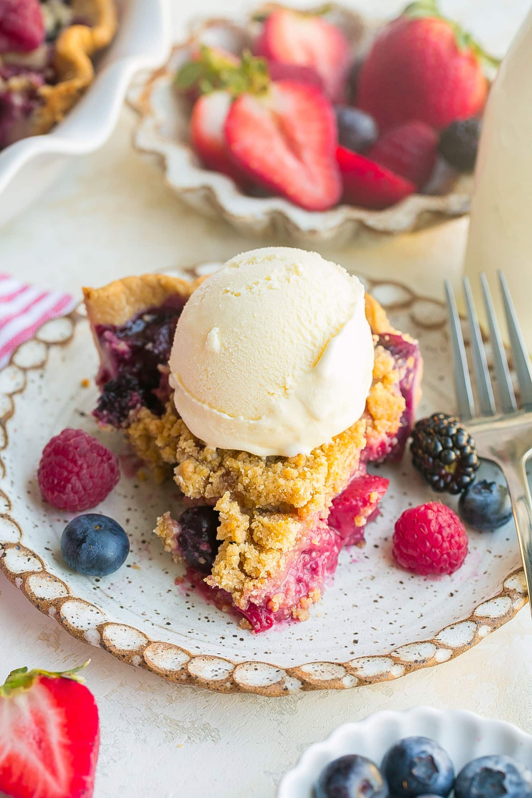 Slice of homemade Berry Crumble Pie served with vanilla ice cream.