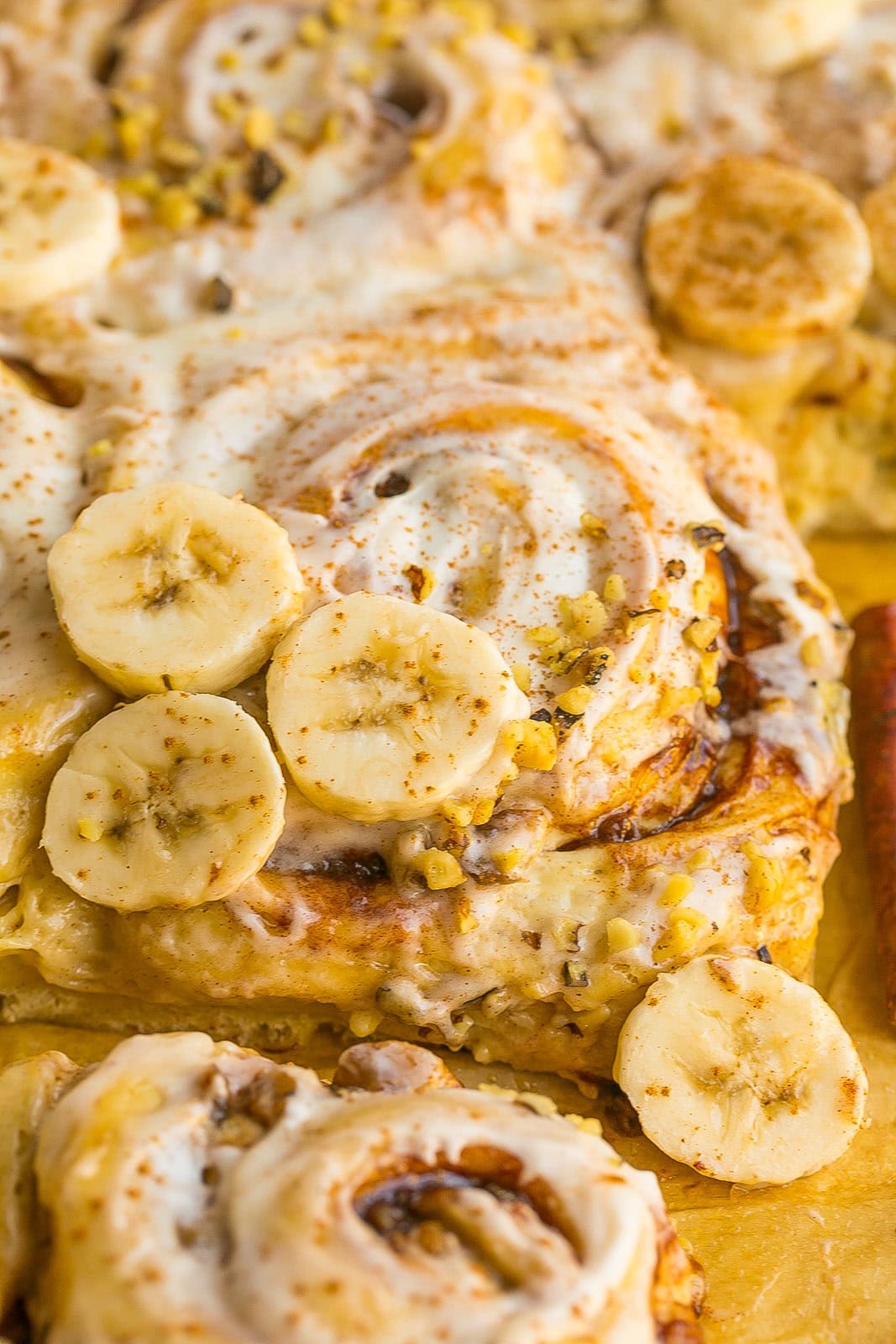 Close up view of a cinnamon roll with bananas and cream cheese frosting.