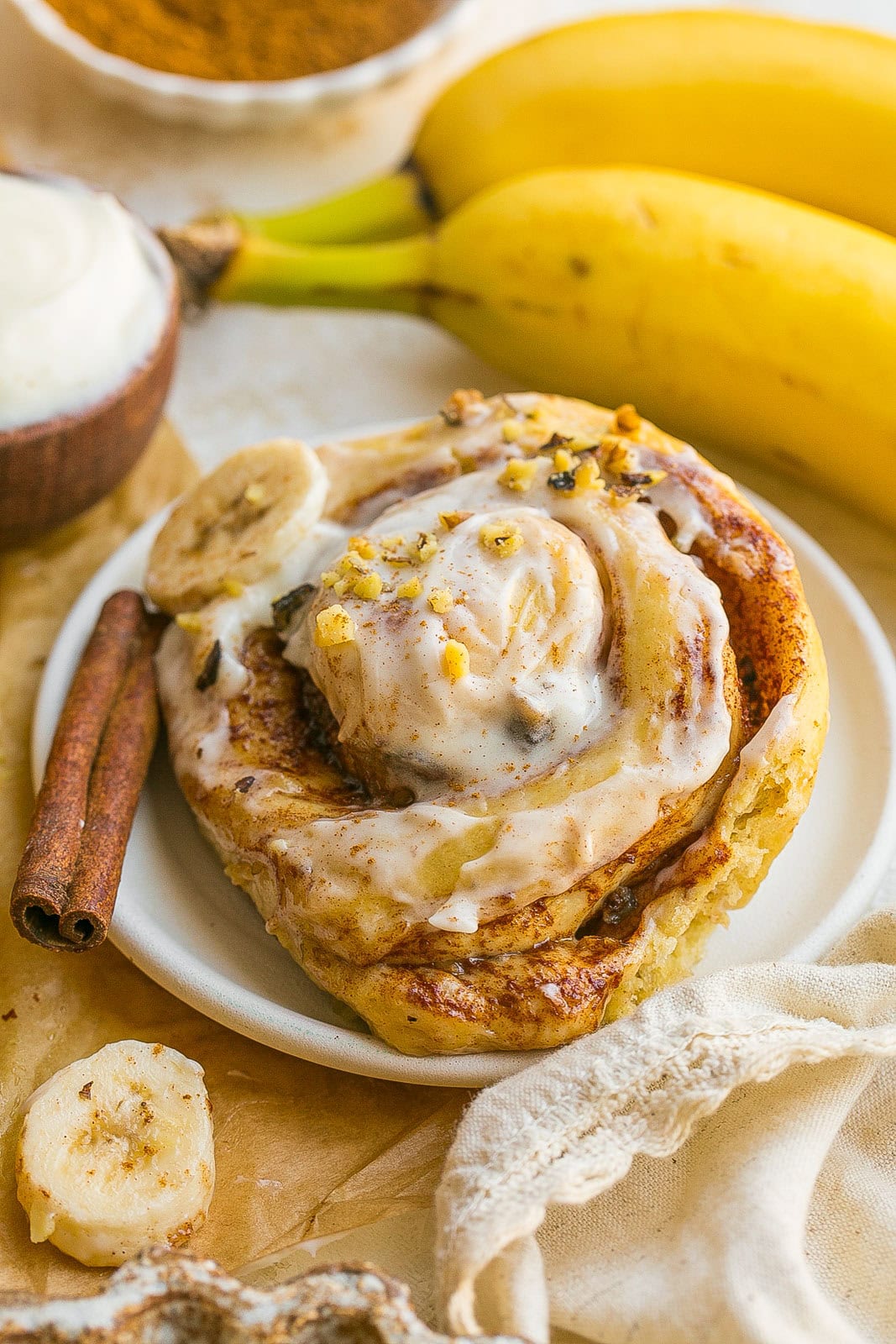 Warm Banana Bread Cinnamon Roll served with cream cheese frosting for breakfast or brunch on a plate.