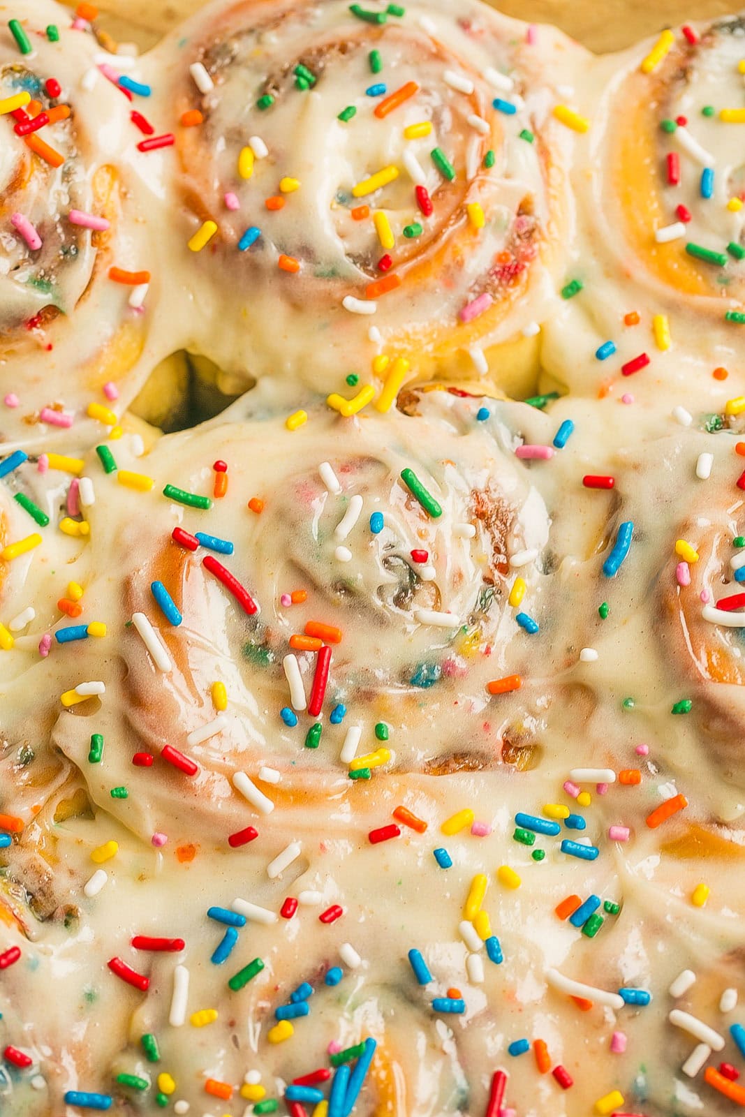 Funfetti Cinnamon Rolls topped with frosting and rainbow sprinkles fresh out of the oven.