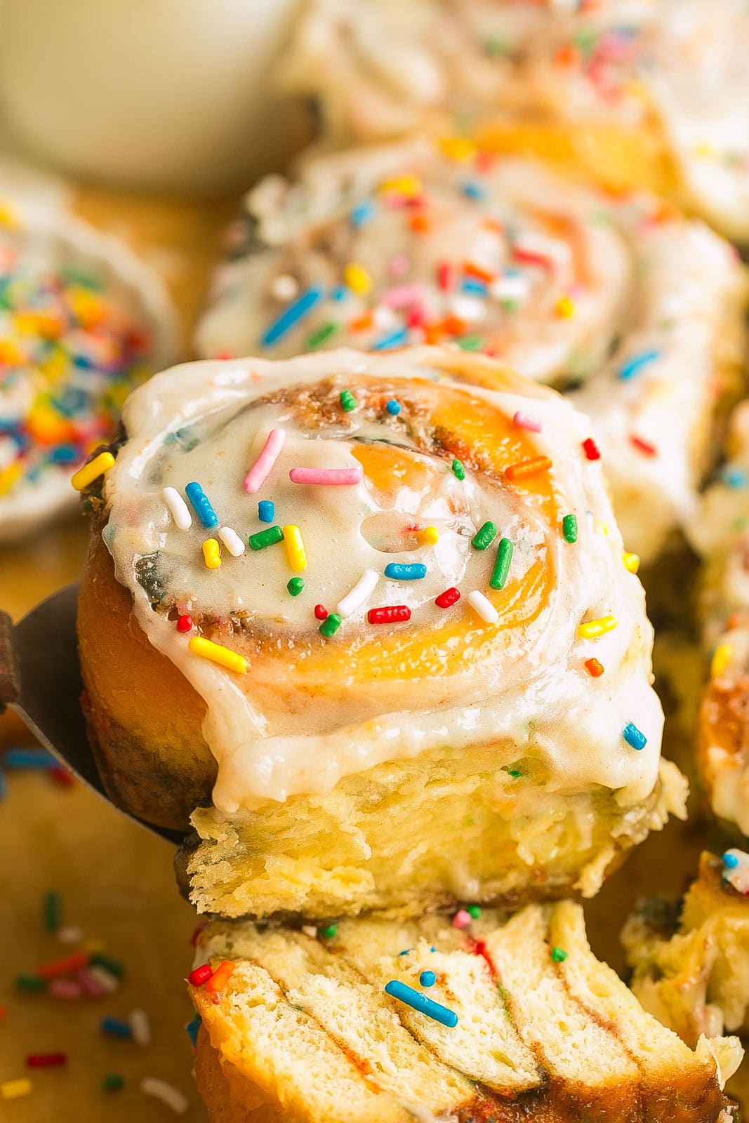 A funfetti sweet roll being pulled from a spatula.