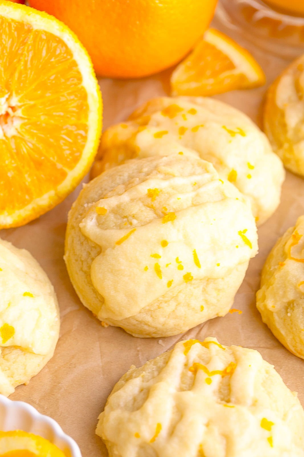Thick bakery-style orange sugar cookies with fresh orange zest and glaze on parchment paper.