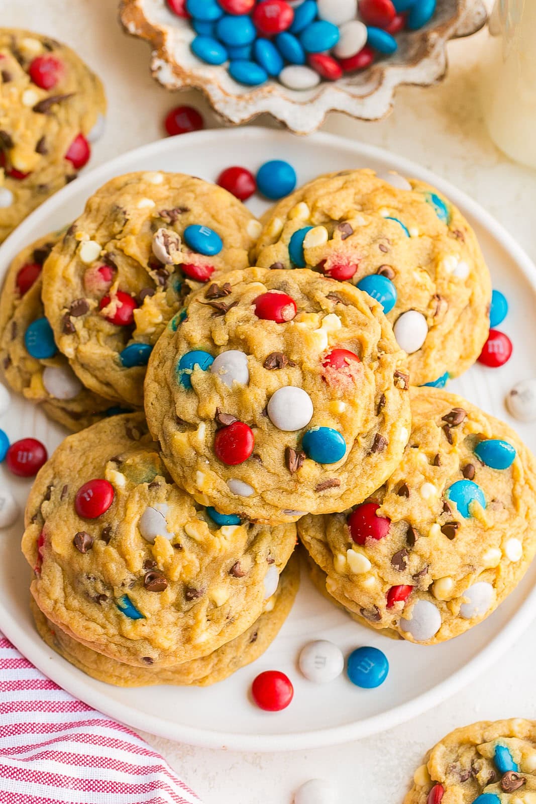 Thick chocolate chip cookies decorated with red white and blue candies on a plate.