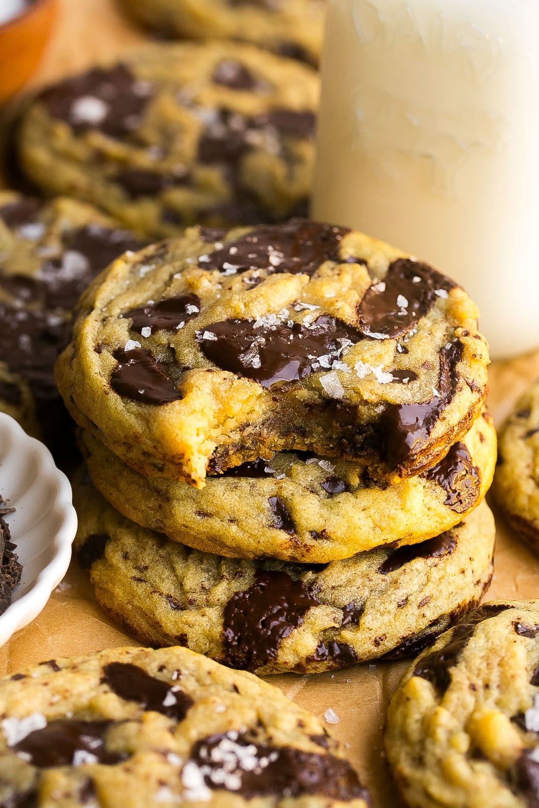 Stack of dark chocolate chip cookies on parchment paper with bite mark.
